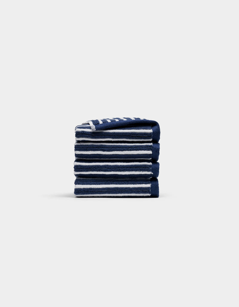 A neatly folded stack of four Cozy Earth Ribbed Terry Washcloths in navy blue and white stripes is centered on a plain, light gray background.