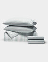 The Cozy Earth Soft-Wash Cotton Bedding Deluxe Bundle includes two pillows, a comforter, and sheets, all neatly folded with a light blue and white vertical stripe pattern.|Color:River and Sea Salt Stripe