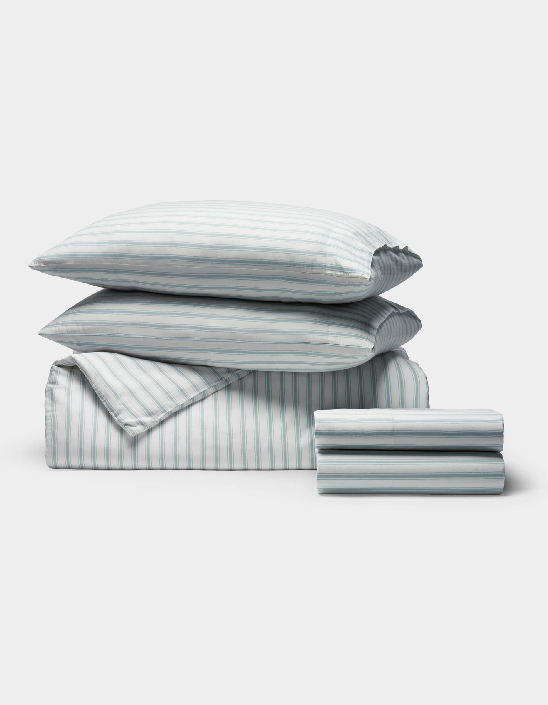 The Cozy Earth Soft-Wash Cotton Bedding Deluxe Bundle includes two pillows, a comforter, and sheets, all neatly folded with a light blue and white vertical stripe pattern.