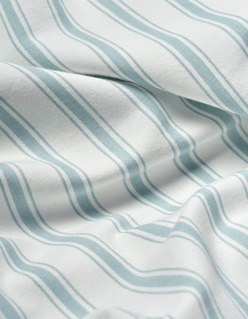 Close-up of Cozy Earth Soft-Wash Cotton Flat Sheet: white fabric with soft, wavy blue-green stripes and slight wrinkles that create gentle shadows and texture.