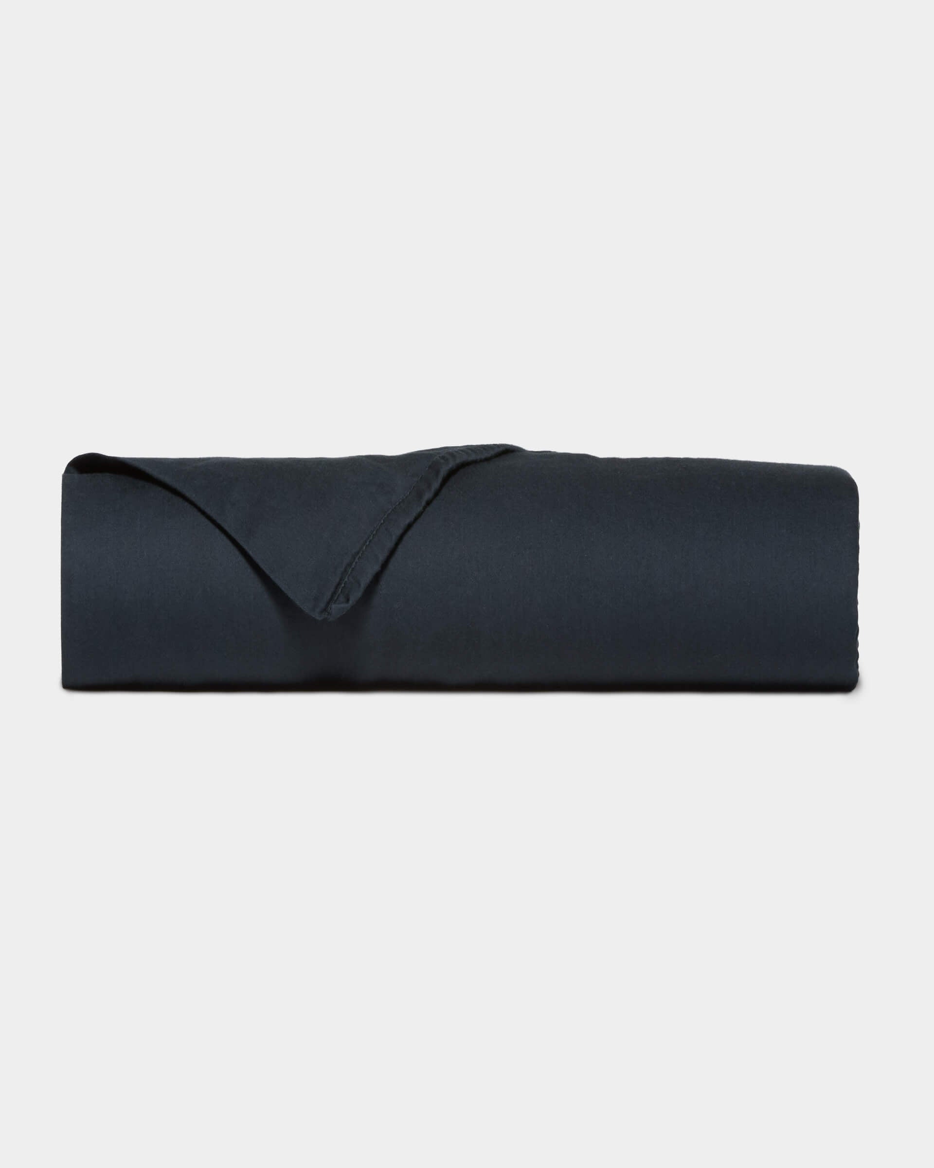 A neatly folded Soft-Wash Cotton Flat Sheet by Cozy Earth in dark navy blue is displayed against a plain light gray background.