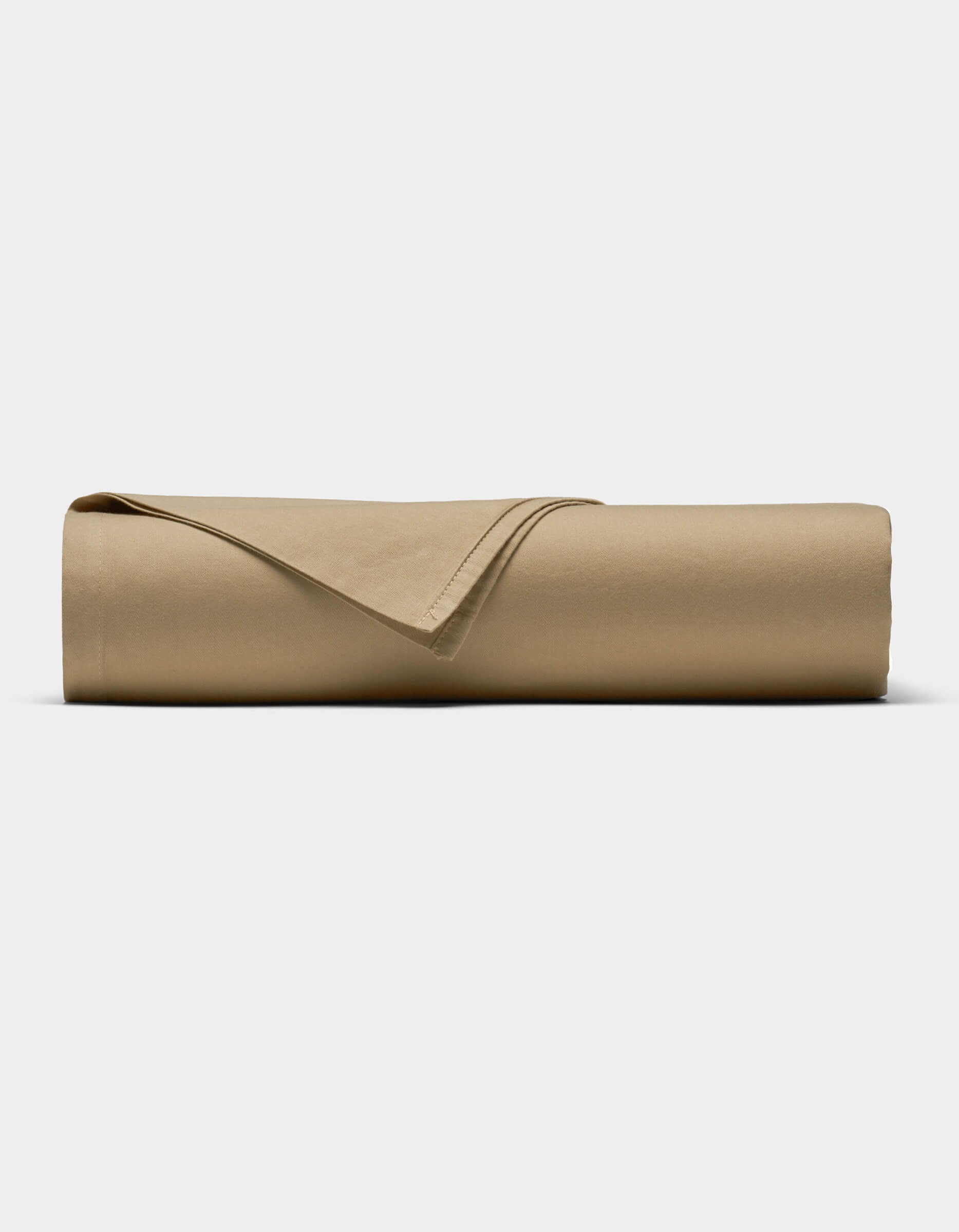 The Soft-Wash Cotton Sheet Set by Cozy Earth in tan is neatly rolled into a cylinder, with one corner folded back, displayed against a plain white background.