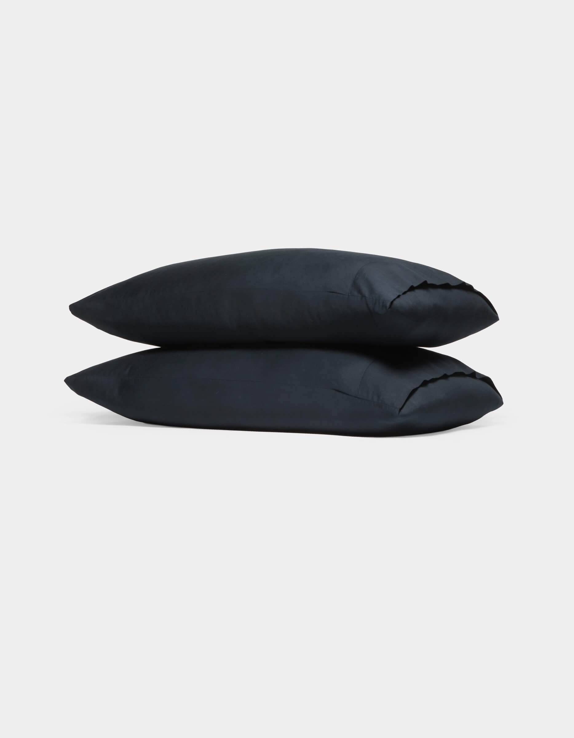 Two Cozy Earth Soft-Wash Cotton Pillowcases in black are stacked atop each other against a plain white background.