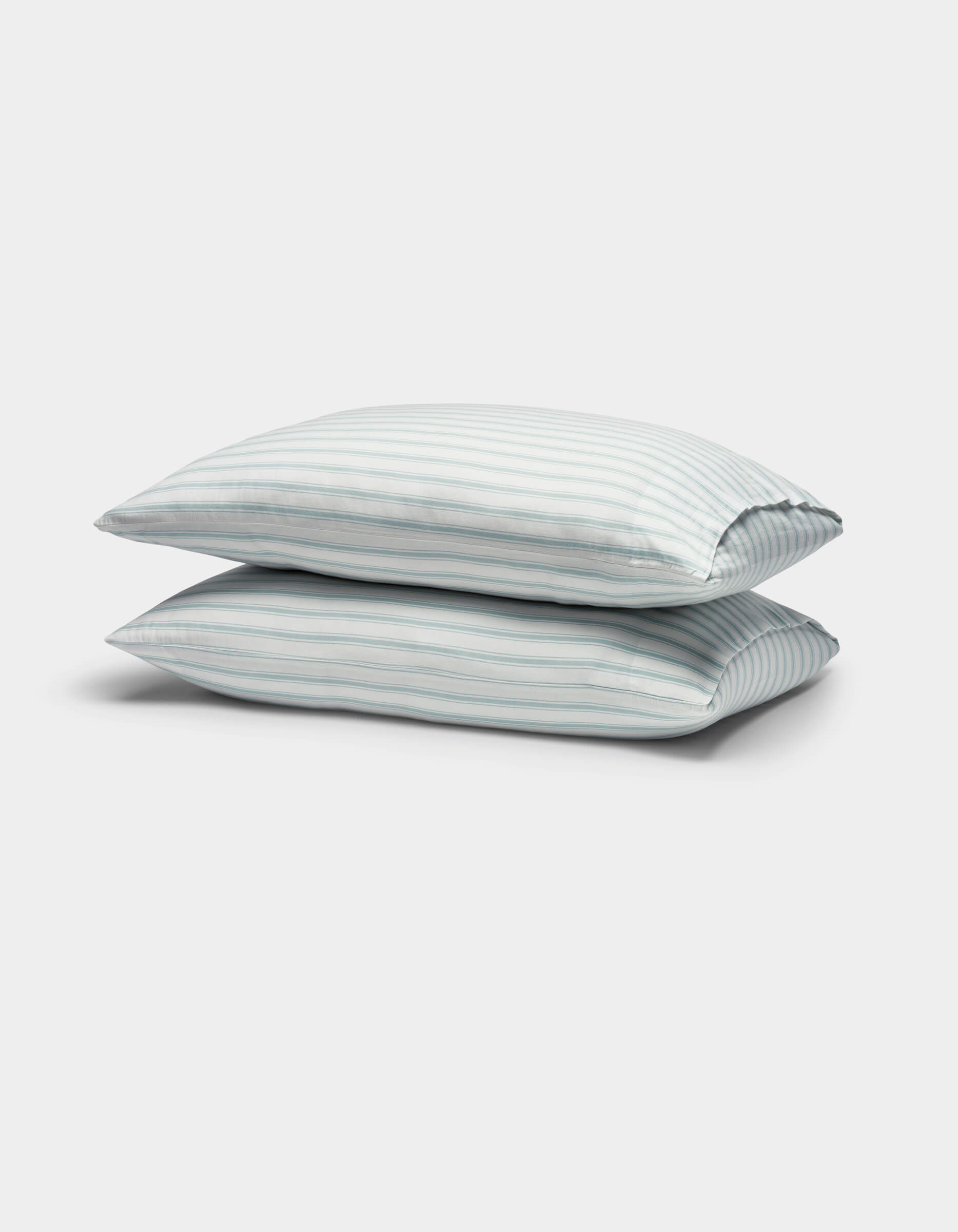 Two Soft-Wash Cotton Pillowcases by Cozy Earth, featuring light blue and white vertical stripes, are stacked against a plain white background.