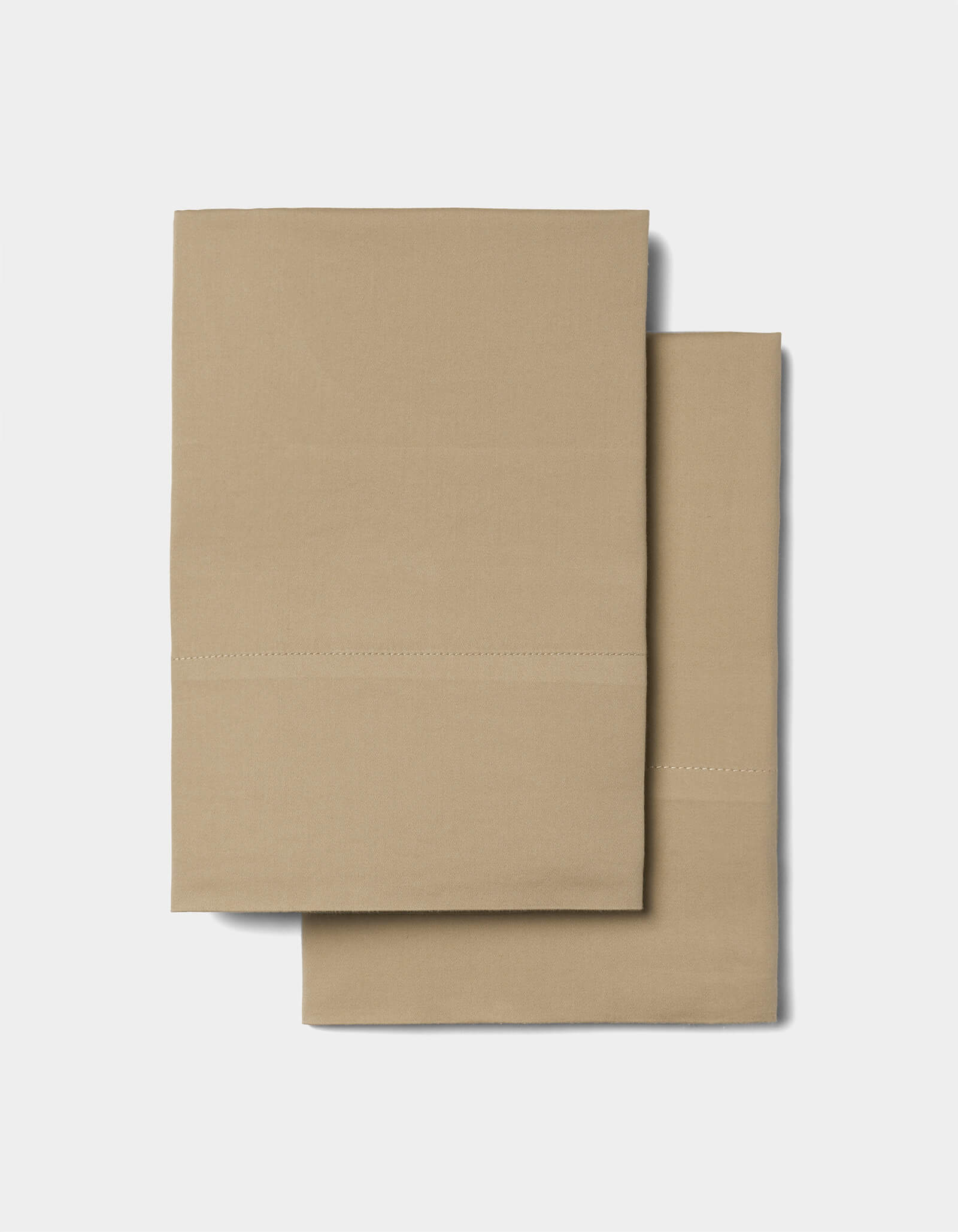 Two folded tan pillowcases from the Cozy Earth Soft-Wash Cotton Sheet Set, featuring a simple stitched line detail, placed on a plain light background.