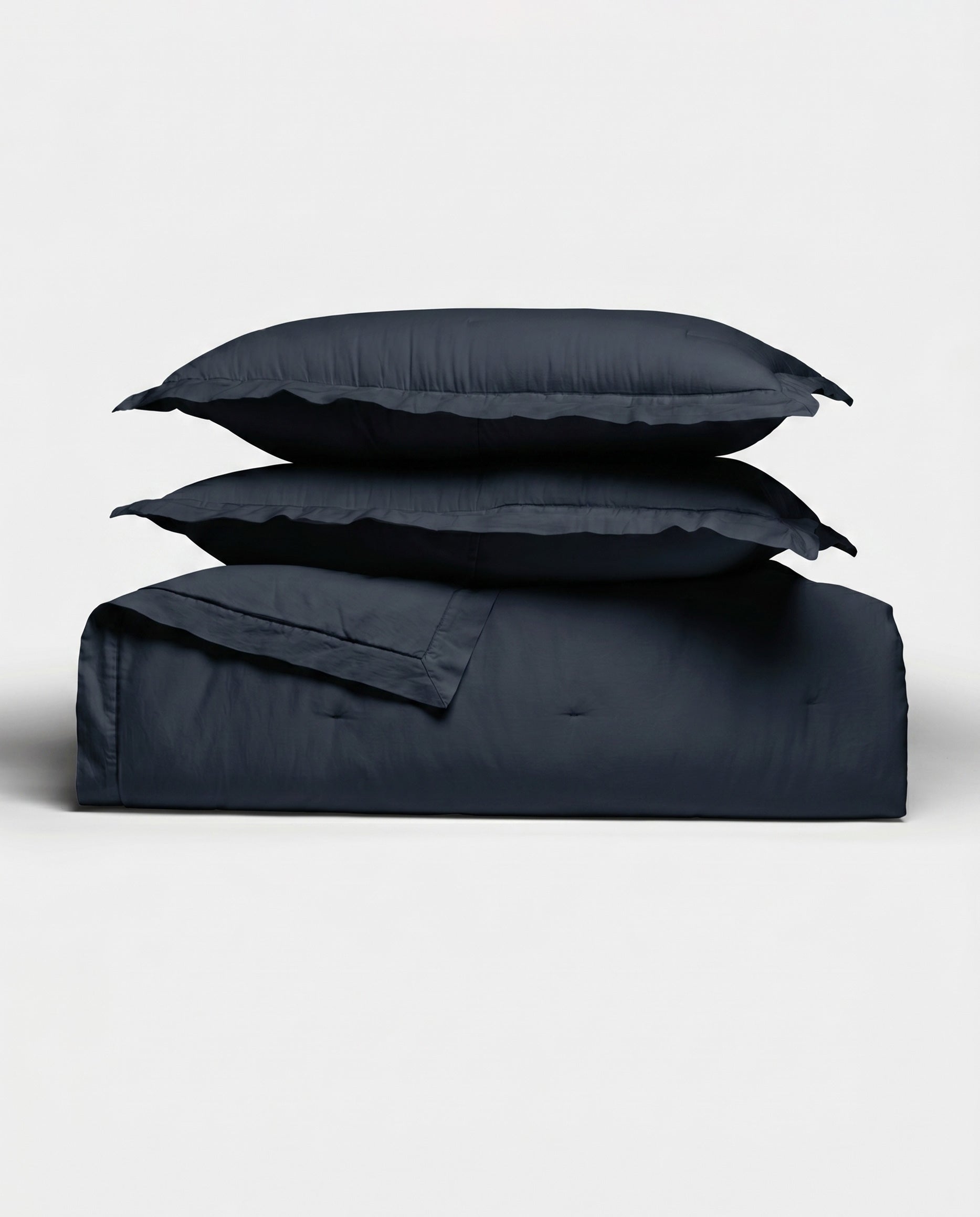 The Cozy Earth Soft-Wash Cotton Quilt Set, featuring a quilt and two pillow shams in dark navy, is neatly stacked against a plain white background.