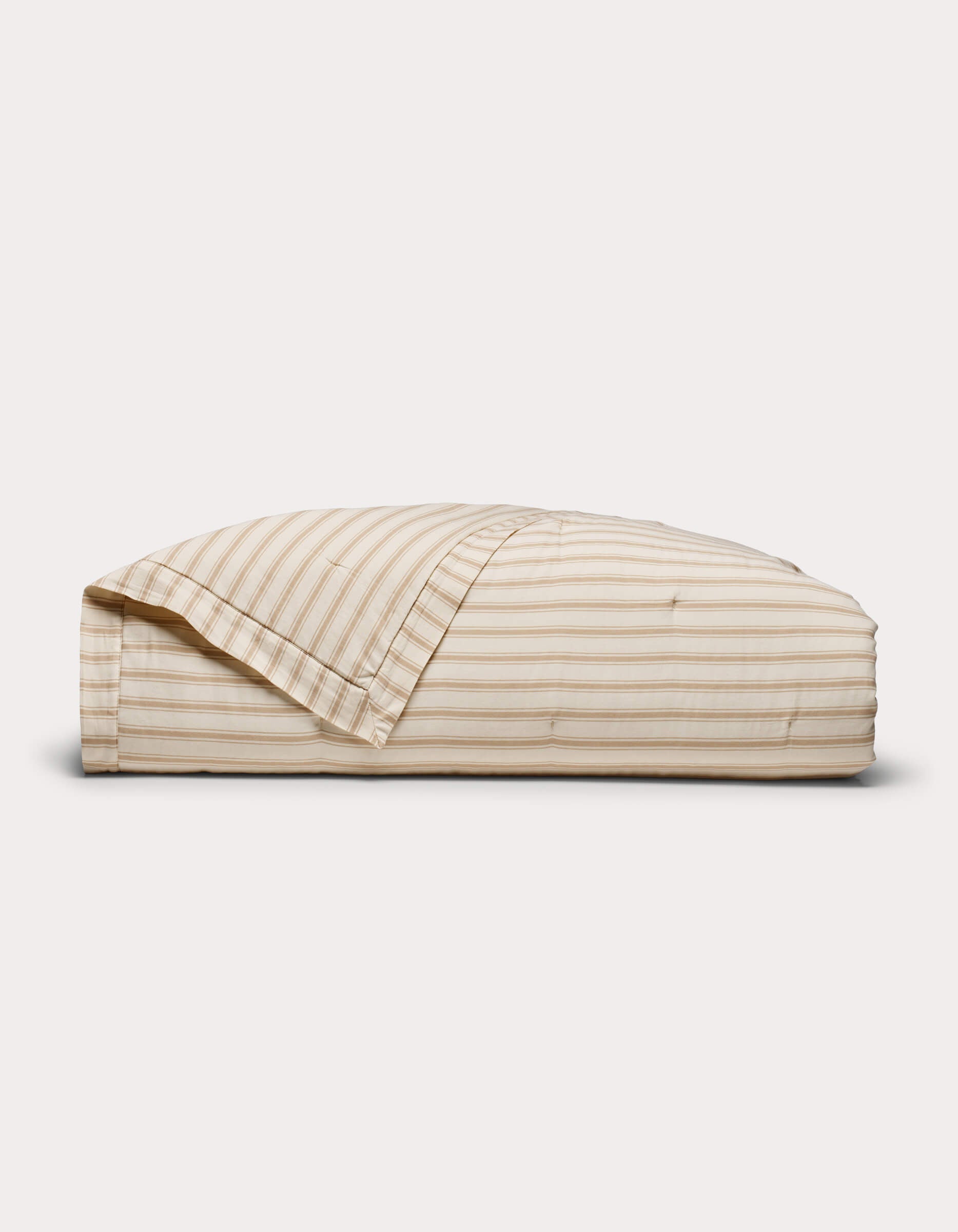 The Cozy Earth Soft-Wash Cotton Quilt, in beige and white stripes, comes neatly folded with a matching pillowcase set against a plain white background.