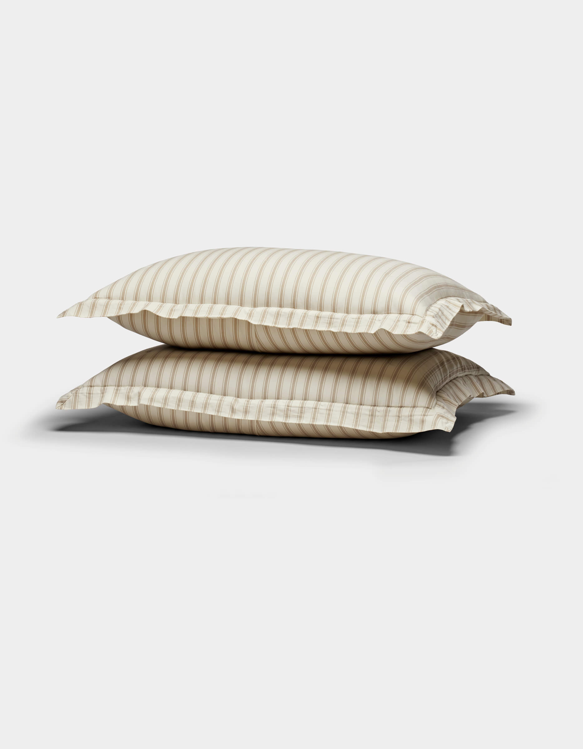 The Soft-Wash Cotton Duvet Set by Cozy Earth is showcased, neatly stacked with its subtle beige tones and gentle horizontal stripes against a plain white background.