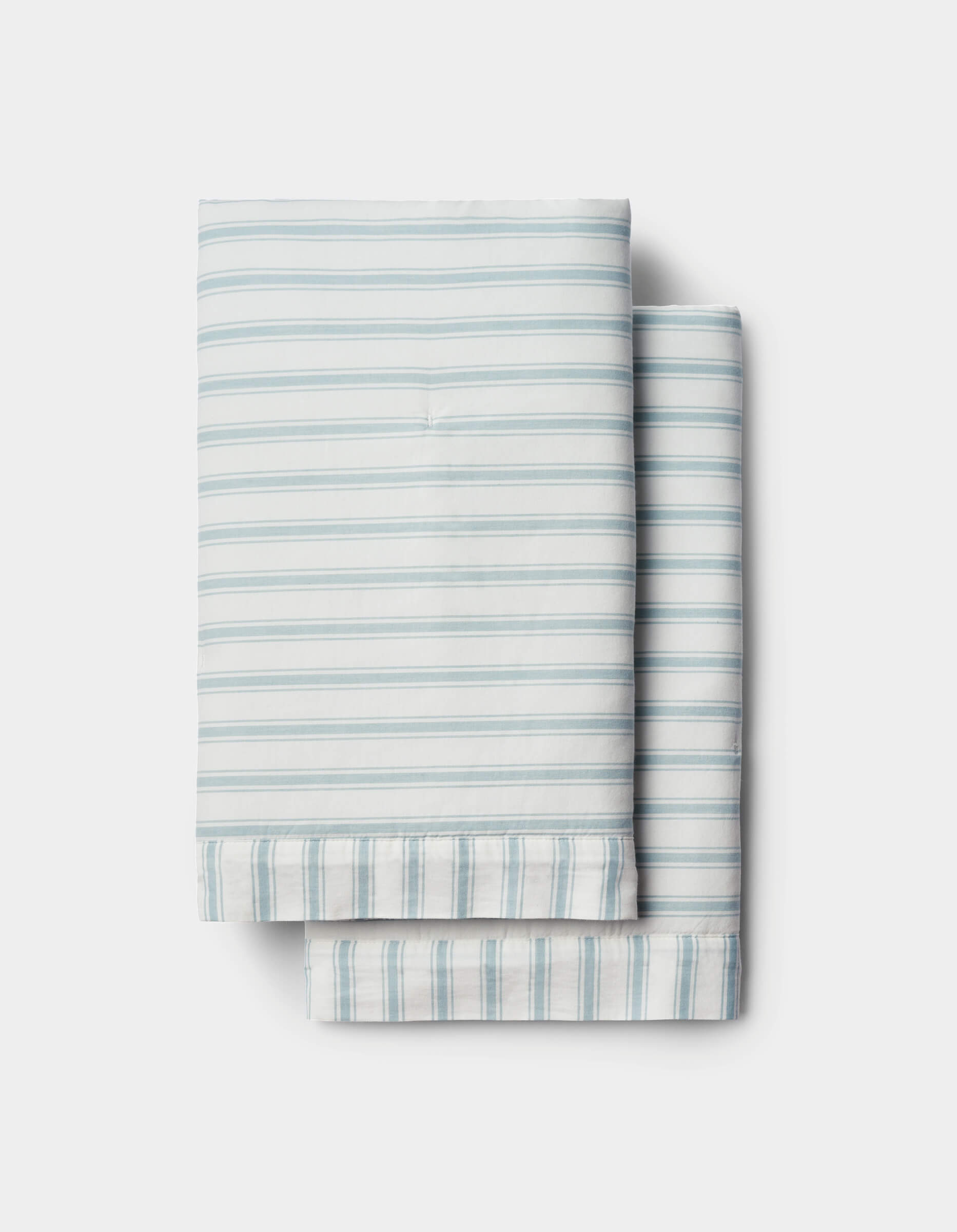 Soft-Wash Cotton Quilted Shams by Cozy Earth in light blue and white stripes are neatly folded and stacked on a white background.