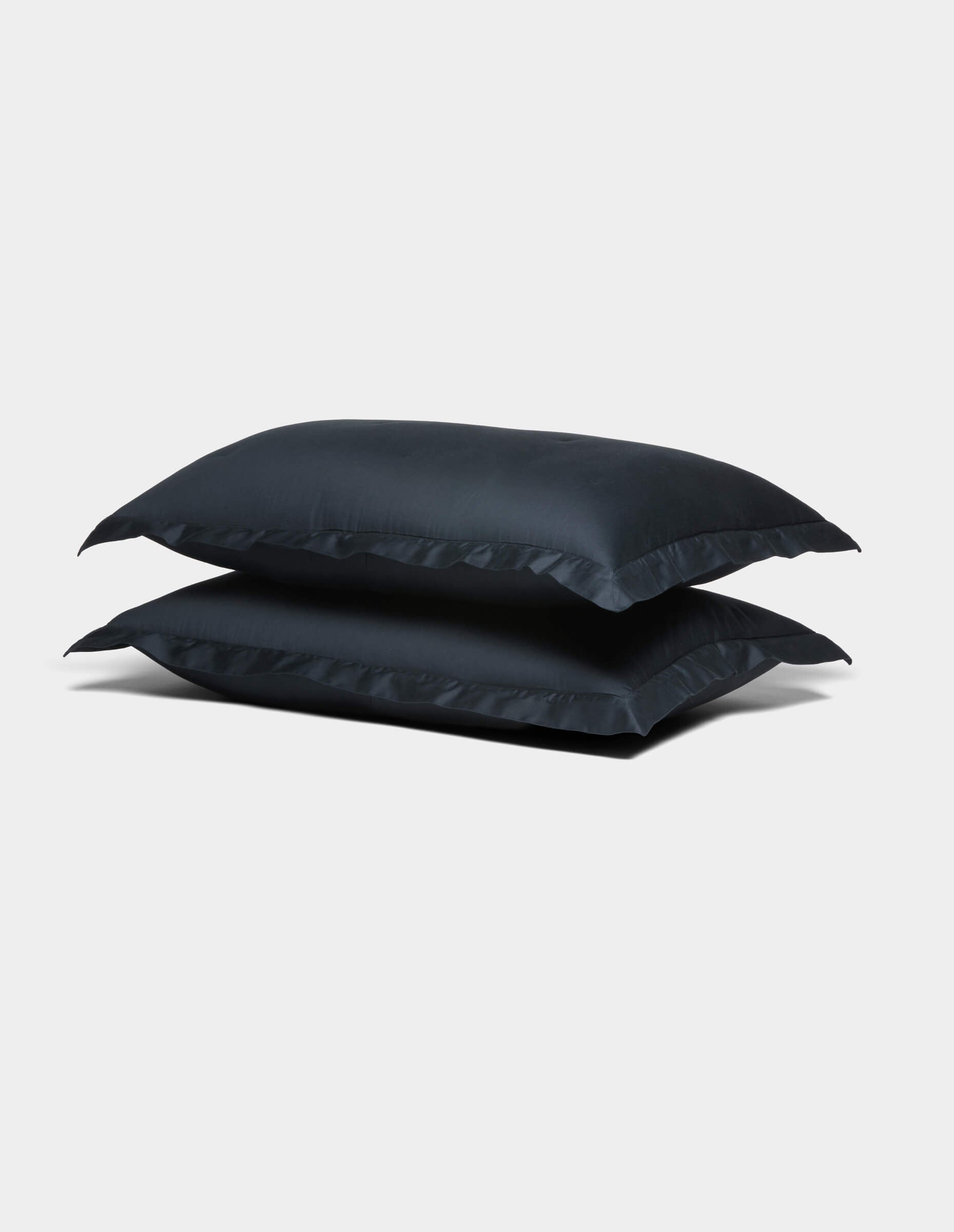 Two Cozy Earth Soft-Wash Cotton Shams in dark blue are stacked on top of each other against a plain light gray background.
