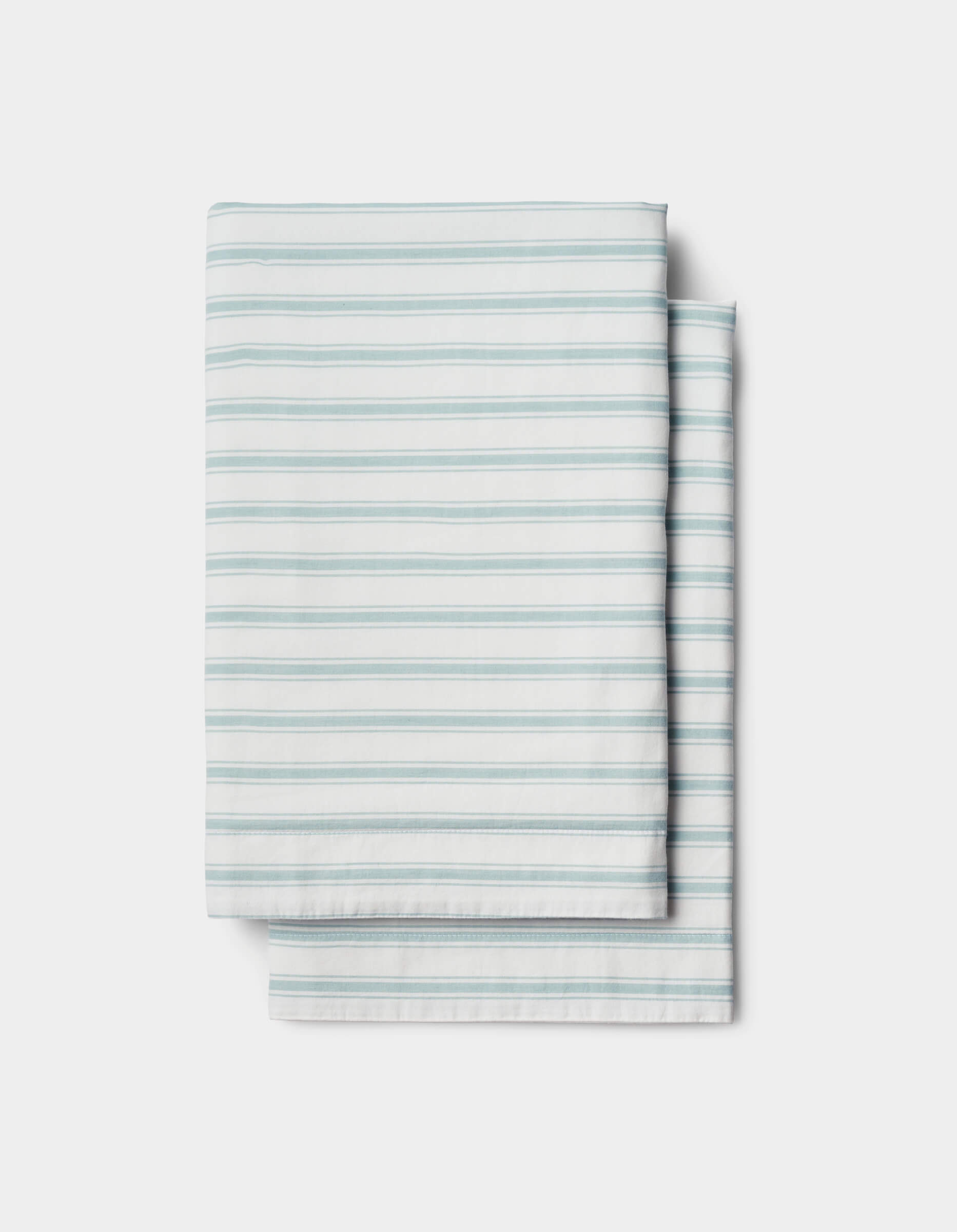 A Soft-Wash Cotton Sham by Cozy Earth, featuring light blue horizontal stripes on white, is neatly folded and set against a plain white background.