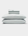 A neatly folded Soft-Wash Cotton Sheet Set by Cozy Earth in light blue and white stripes, featuring two stacked pillows and a folded fitted sheet, displayed on a plain white background.|Color:River and Sea Salt Stripe