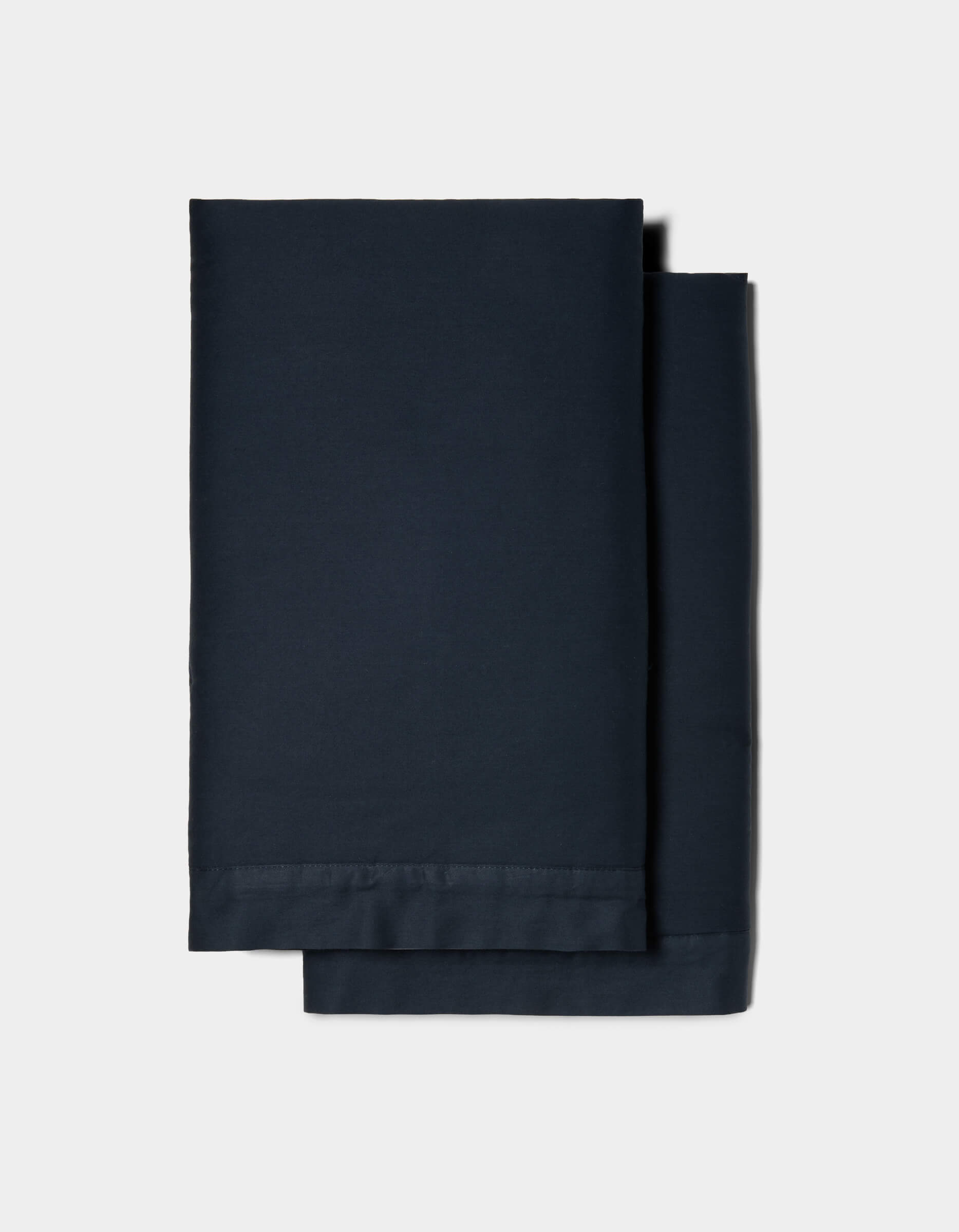 Two neatly folded Soft-Wash Cotton Shams by Cozy Earth, in dark navy blue, stacked together against a plain light gray background.