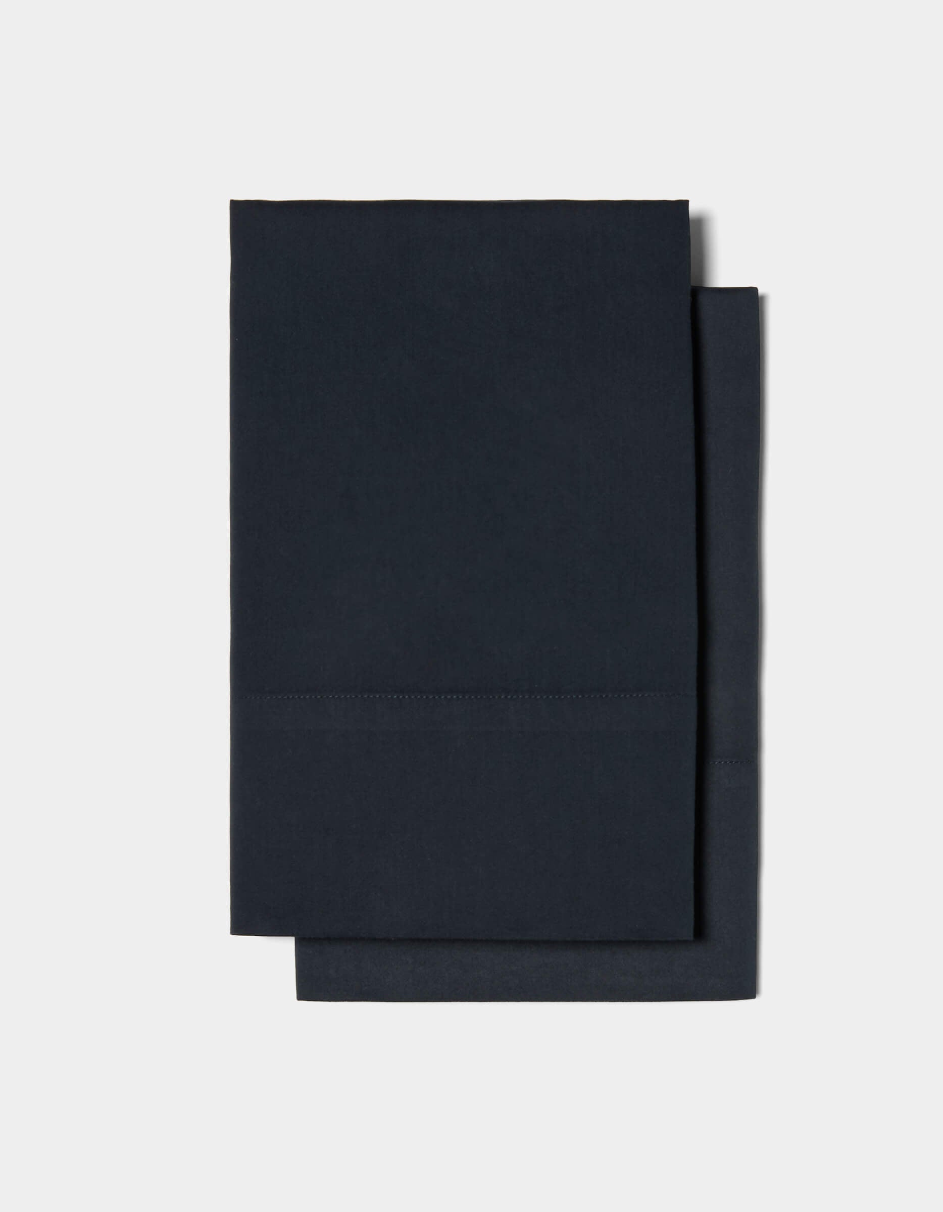 Two neatly folded Soft-Wash Cotton Pillowcases by Cozy Earth are stacked on top of each other against a plain white background.