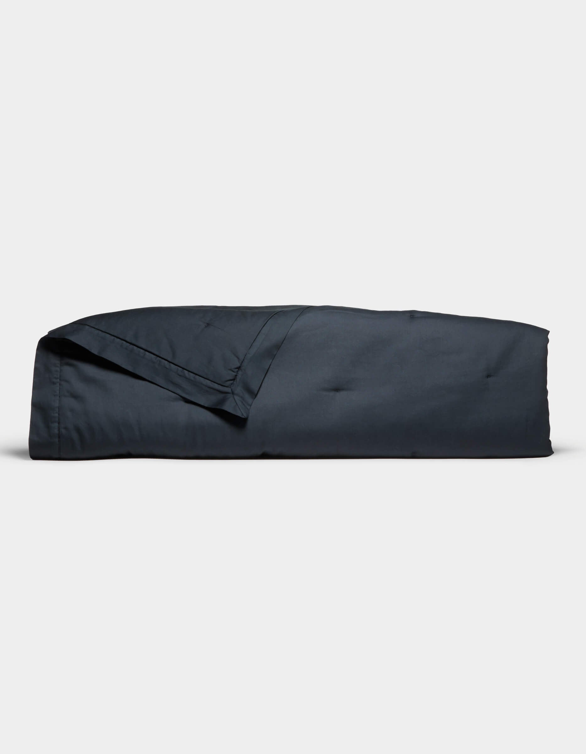 The Cozy Earth Soft-Wash Cotton Quilt set, in dark blue, is neatly folded and displayed against a plain white background. It includes a quilt and matching pillowcase, both looking soft and smooth.