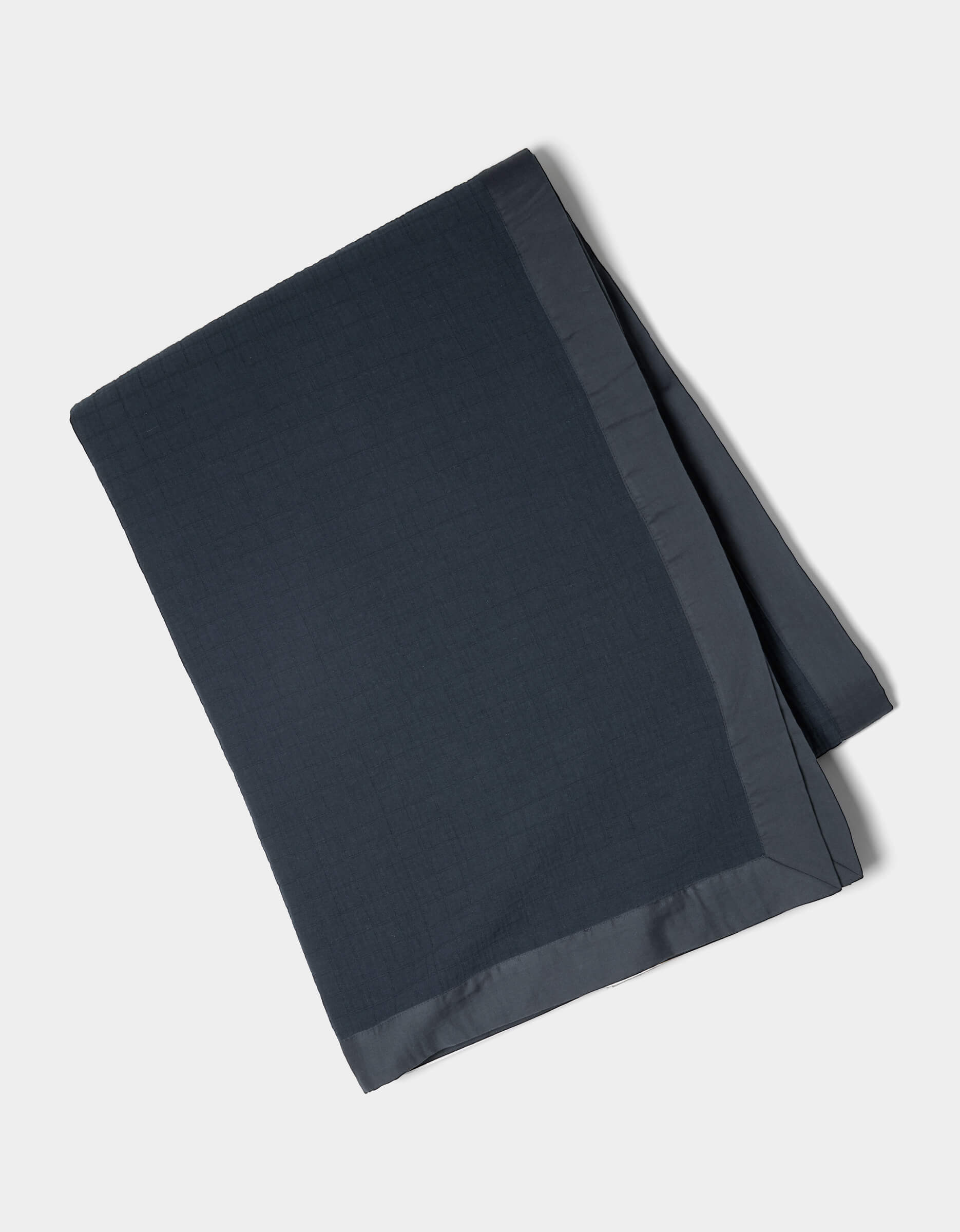 The Cozy Earth Waterfront Grid Matelasse Blanket, shown neatly folded in dark blue with a smooth satin border, is displayed on a plain light background.