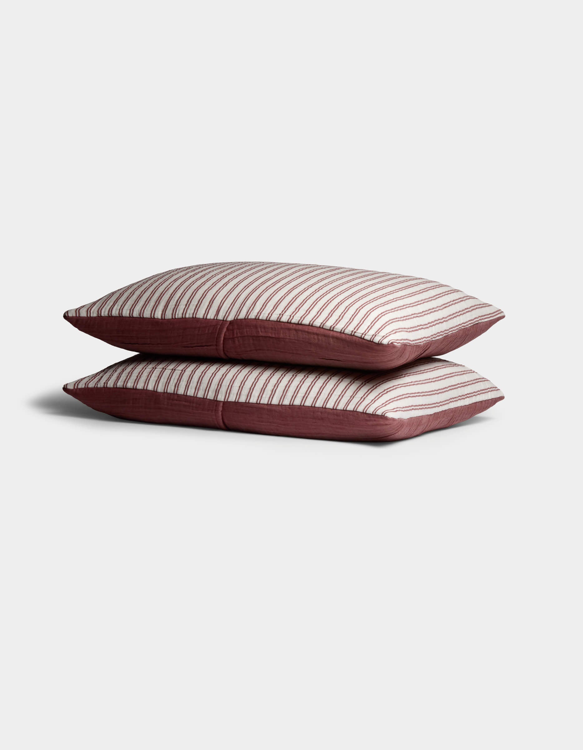 Two Waterfront Shams by Cozy Earth are stacked, showing a white top with thin horizontal red stripes and solid red sides, set against a plain light background.