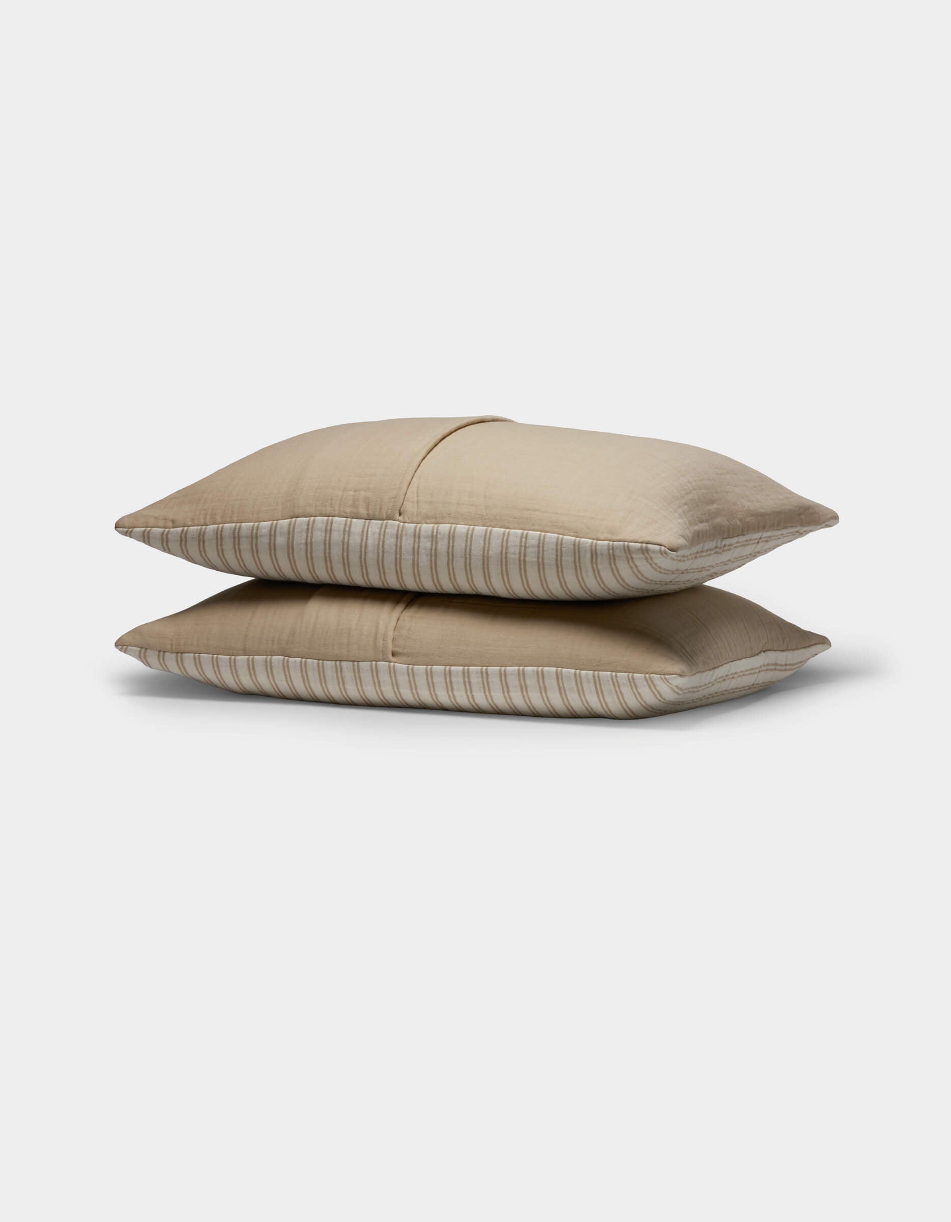 Two Cozy Earth Waterfront Shams in light brown with subtle horizontal stripes are stacked together against a plain white background.