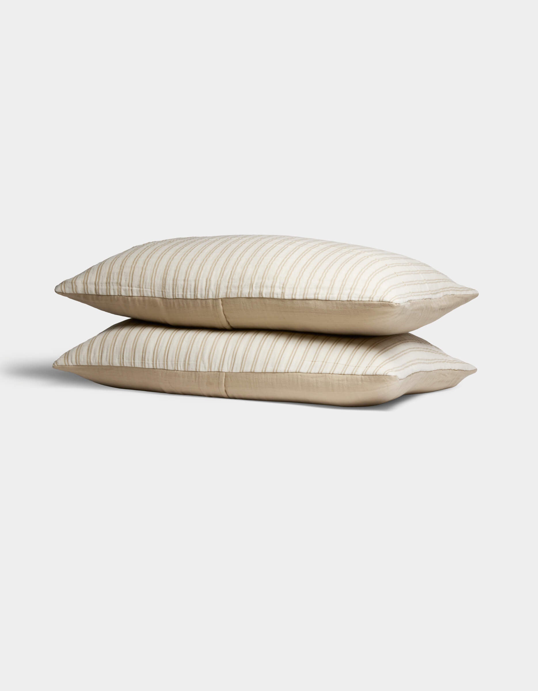 Two Cozy Earth Waterfront Shams in beige, featuring subtle horizontal stripes, are stacked against a plain white background.