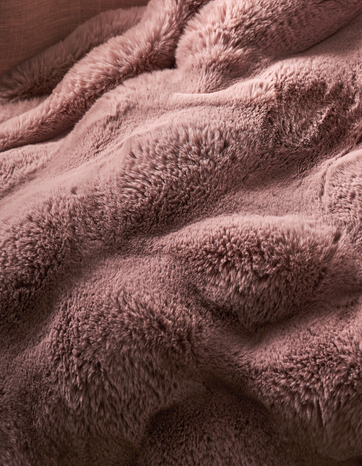 The Double Bubble Cuddle Blanket from Cozy Earth features soft, fluffy light pink faux fur with gentle folds and a wavy texture, creating a cozy and warm look.