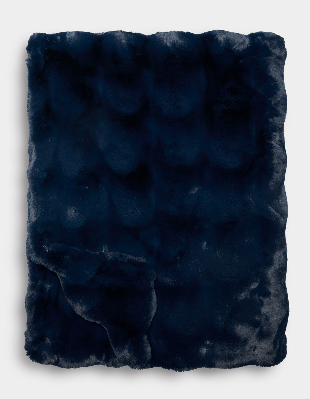 The Double Bubble Cuddle Blanket by Cozy Earth, in dark navy blue faux fur, is folded neatly to display its plush, soft texture and subtle sheen against a plain white background.