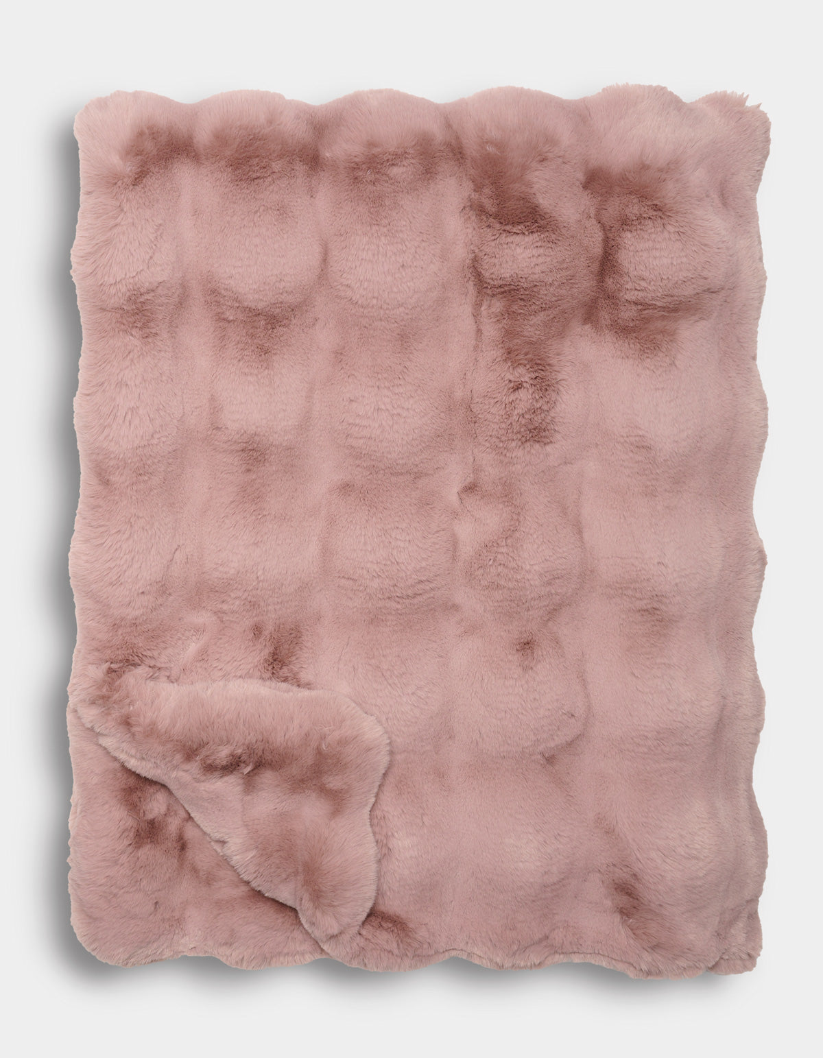 The Double Bubble Cuddle Blanket by Cozy Earth is a folded, blush pink faux fur blanket featuring a textured, slightly quilted pattern and an irresistibly soft, plush appearance.