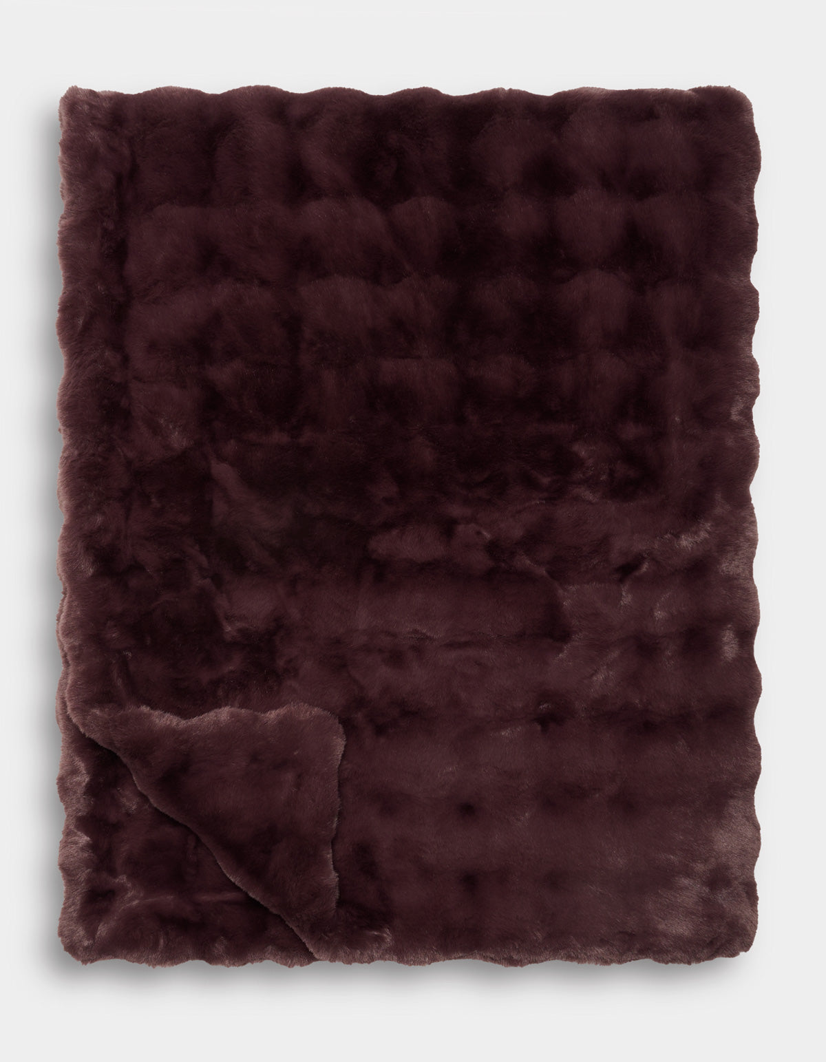 A Bubble Cuddle Blanket by Cozy Earth is displayed folded with one corner turned up, revealing its soft texture and subtle checkered pattern.