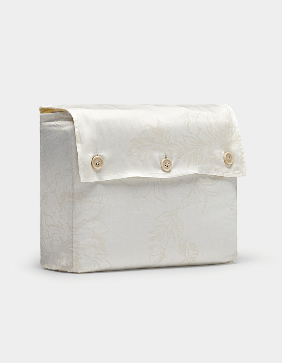 A Cozy Earth Bamboo Sheet Set folded inside its matching cream fabric packaging with a three-button flap, featuring a subtle floral pattern and displayed on a plain white background.