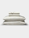 A Cozy Earth Bamboo Sheet Set in cream, featuring a subtle floral pattern, with two pillows in matching pillowcases stacked beneath neatly folded sheets, displayed on a plain white background.|Color:Sonoma Floral in Vintage White