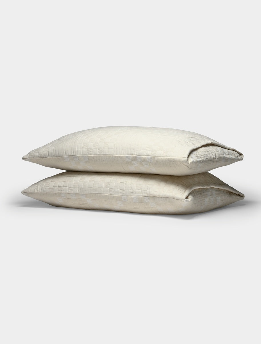 Two Sonoma Stitch Shams by Cozy Earth, featuring a subtle checkered pattern in a cream color, are stacked atop each other against a plain white background.|Color:Vintage White