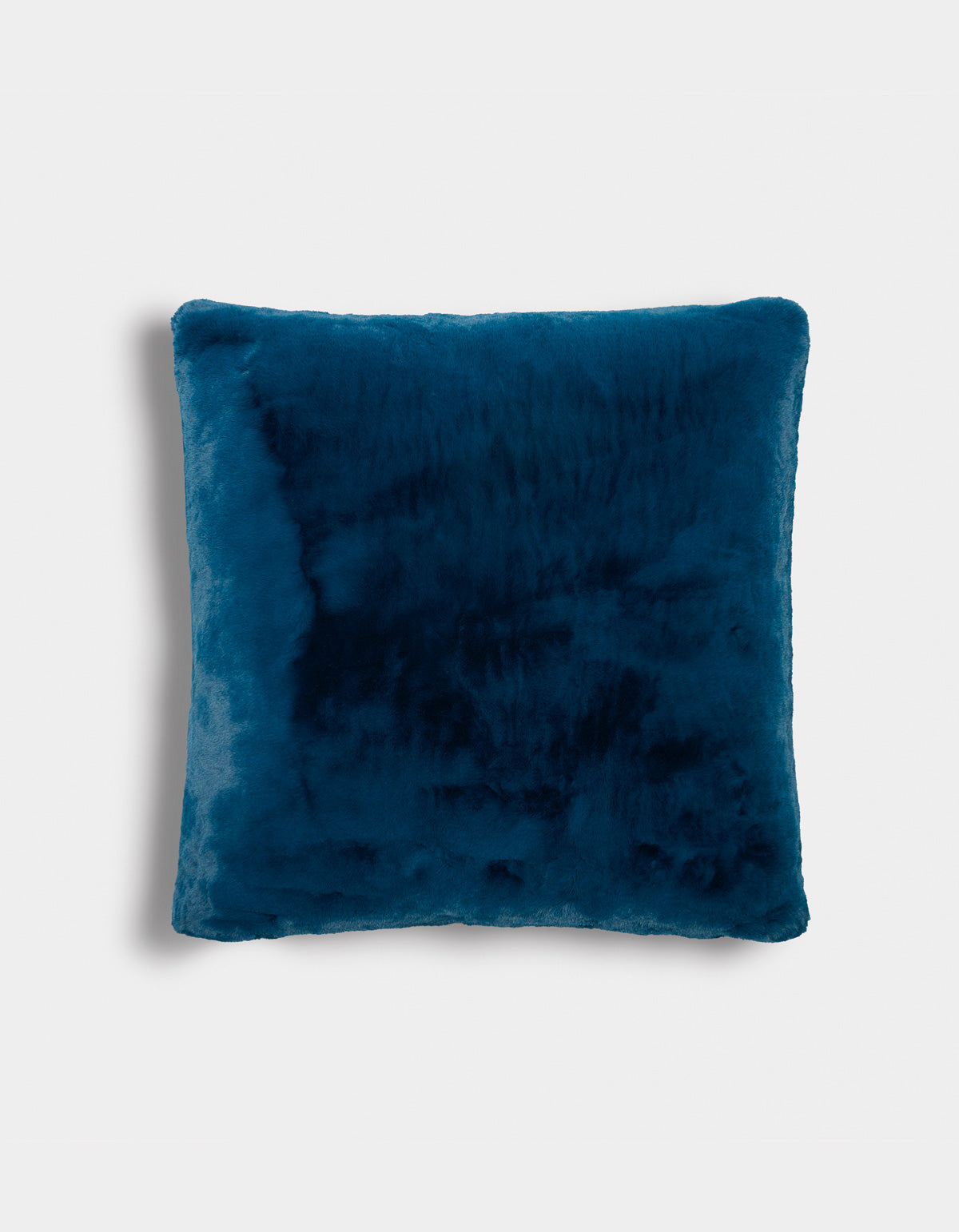 The Superplush Cuddle Pillow by Cozy Earth, featuring a square shape and deep blue faux fur, is displayed against a plain white background. Its soft and plush texture is evident, with gently rounded edges and a subtle shadow on the left side.