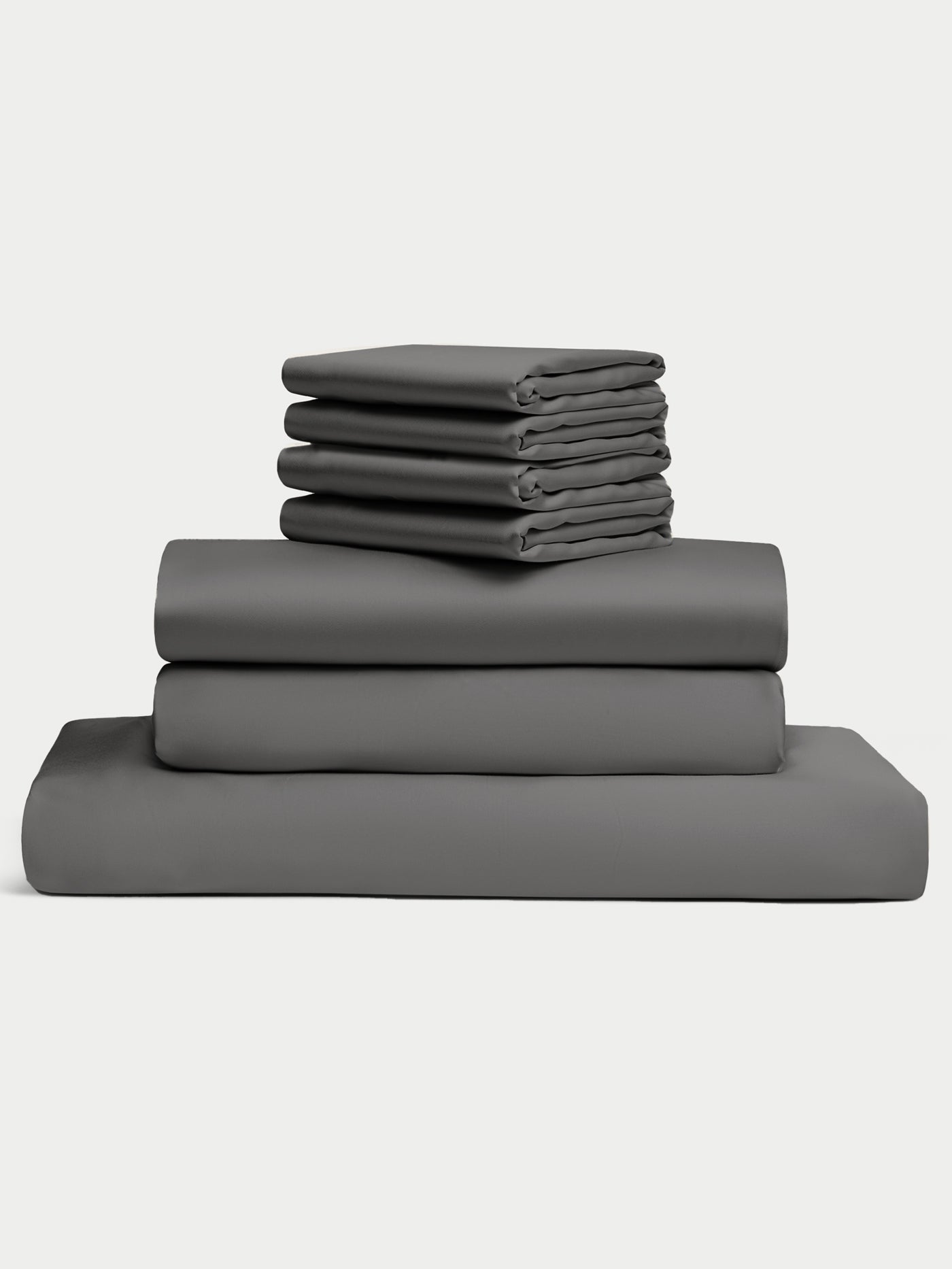 Set of gray bedding including sheet, a duvet cover and pillowcases on a white background. 