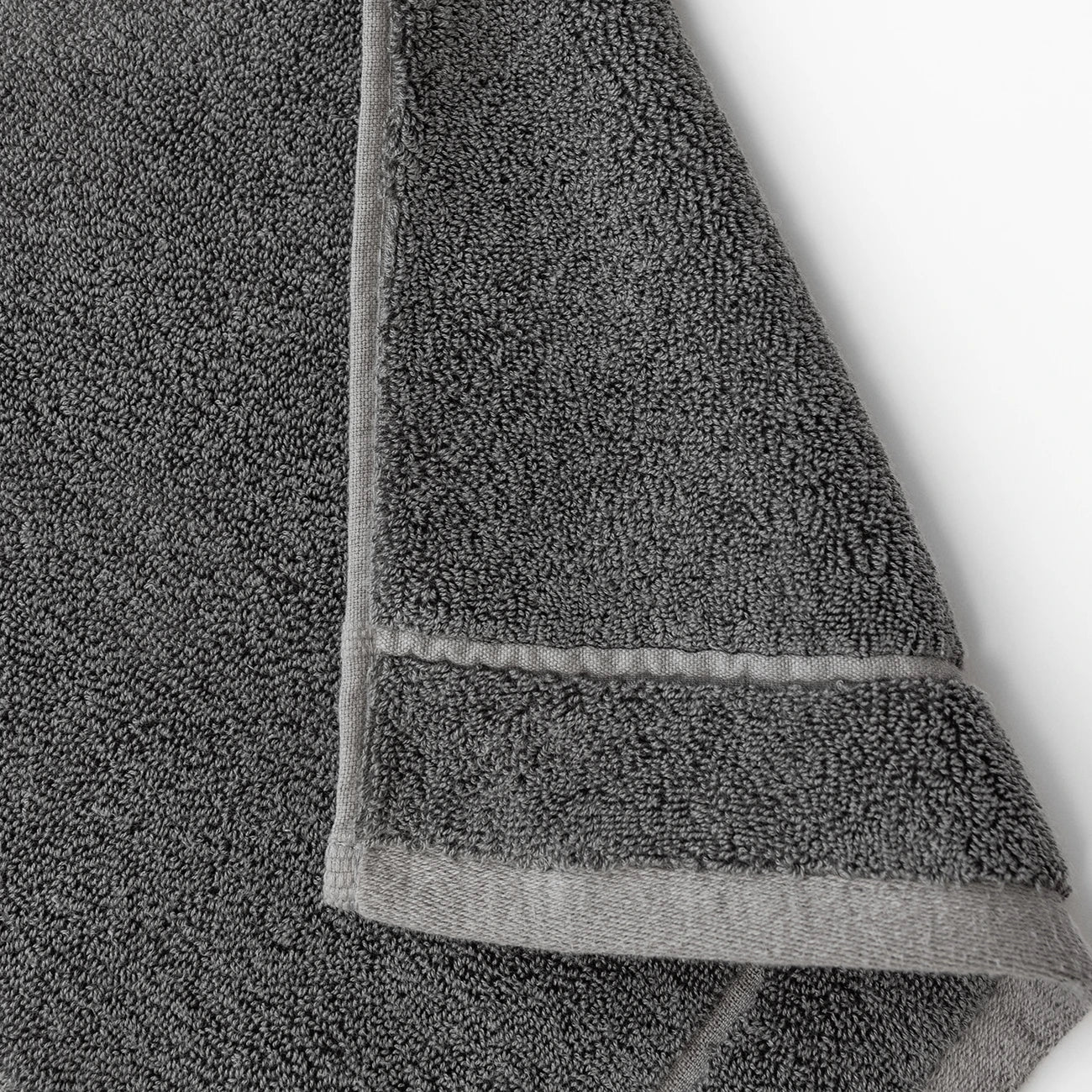 The photograph features a close-up of Cozy Earth's Premium Plush Washcloths in dark gray, highlighting the stitched edges and textured, looped terry cloth surface against a plain white background.