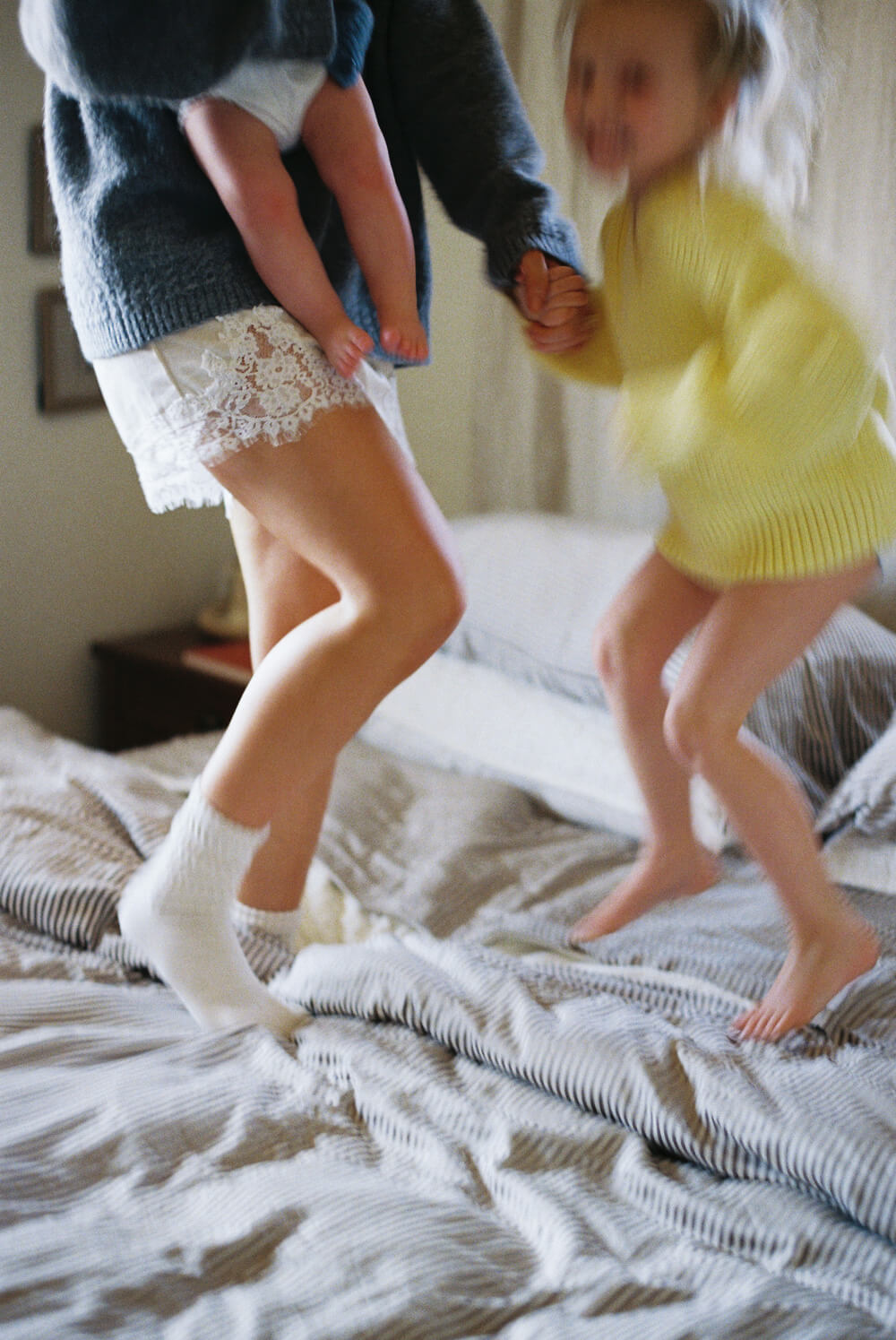 Two children playing on a bed with one wearing white socks.