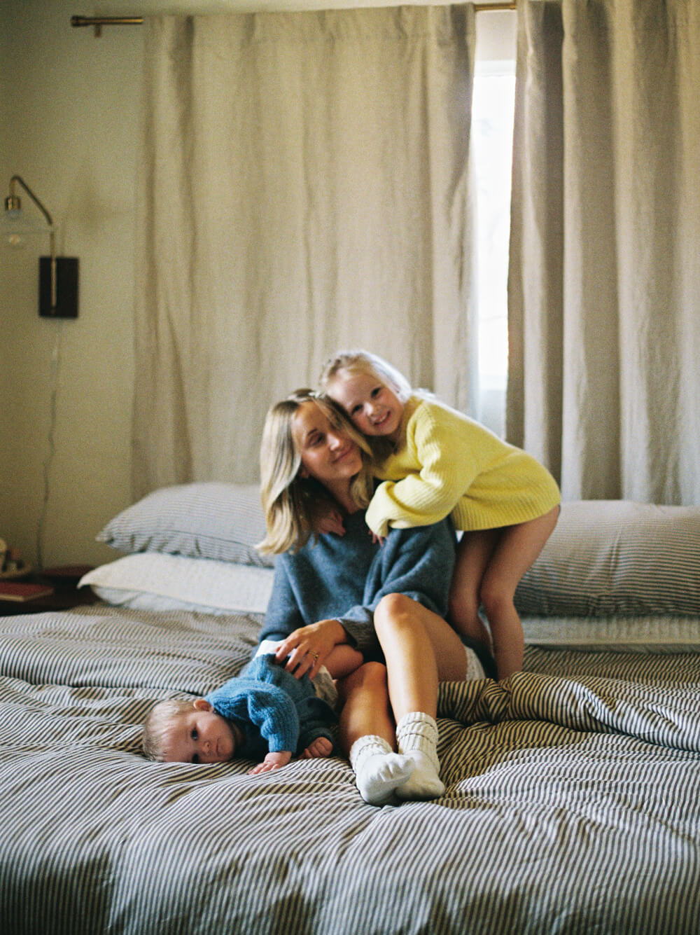Woman and two children on a bed in a bedroom setting