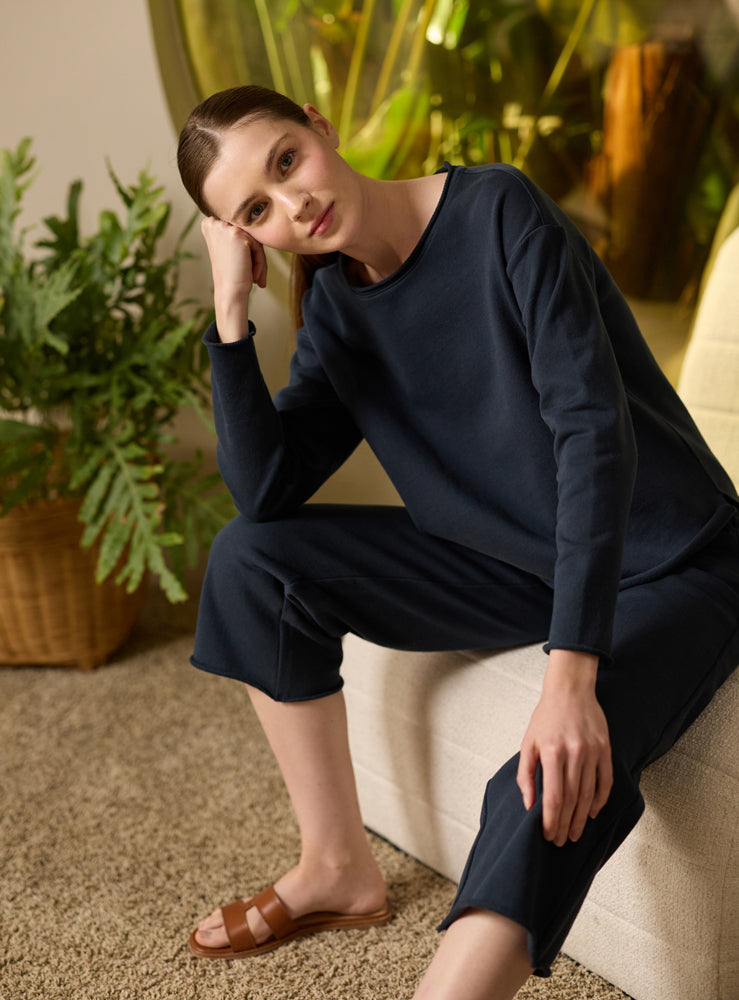 Woman in navy blue Cozy Earth Chelsea Set sitting on a white chair with plants in the background