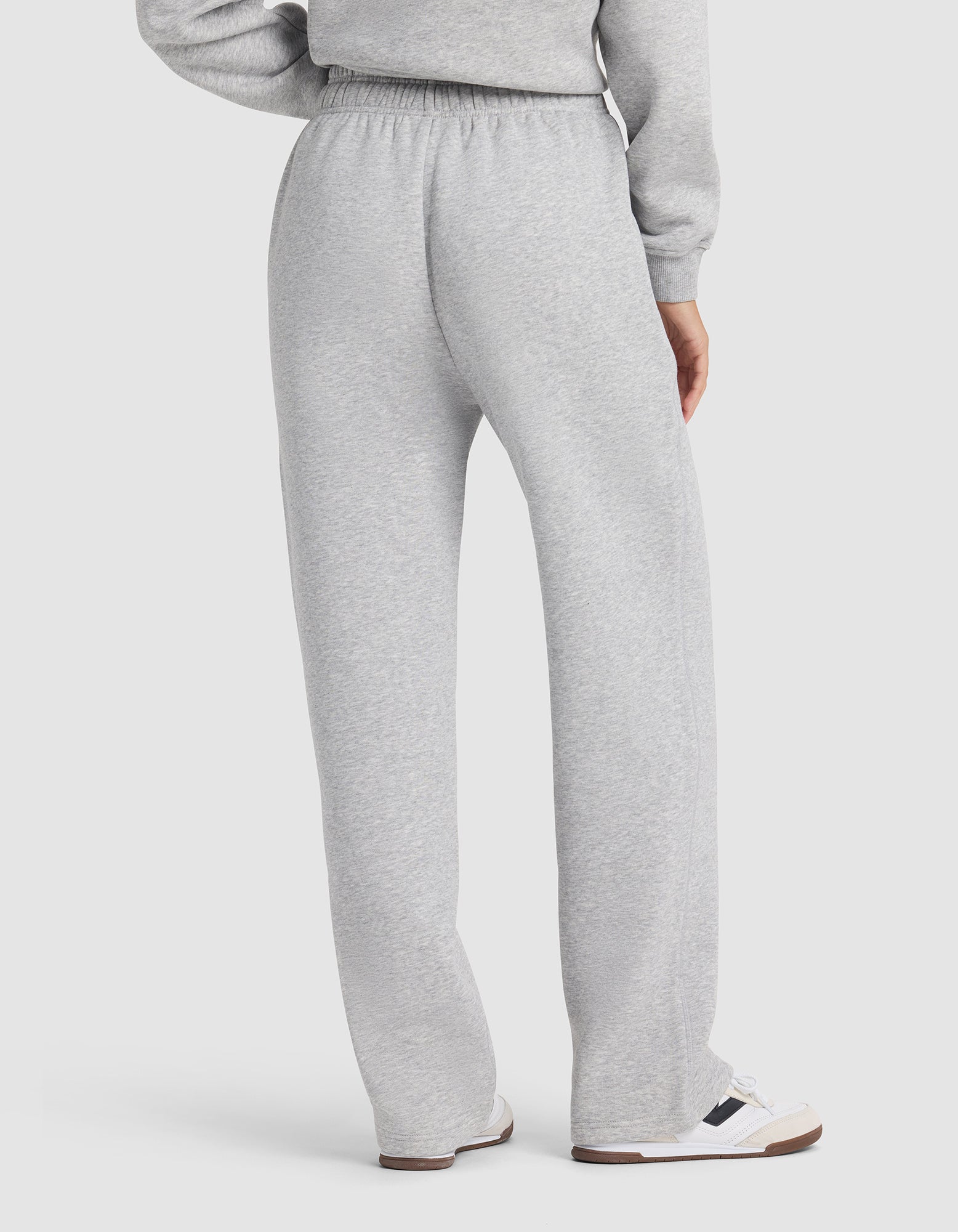 Seen from the back, a person wears Cozy Earth's Women's Cityscape 2.0 Wide Leg Pant in light gray with a matching sweatshirt and white sneakers with dark accents, set against a plain white background.