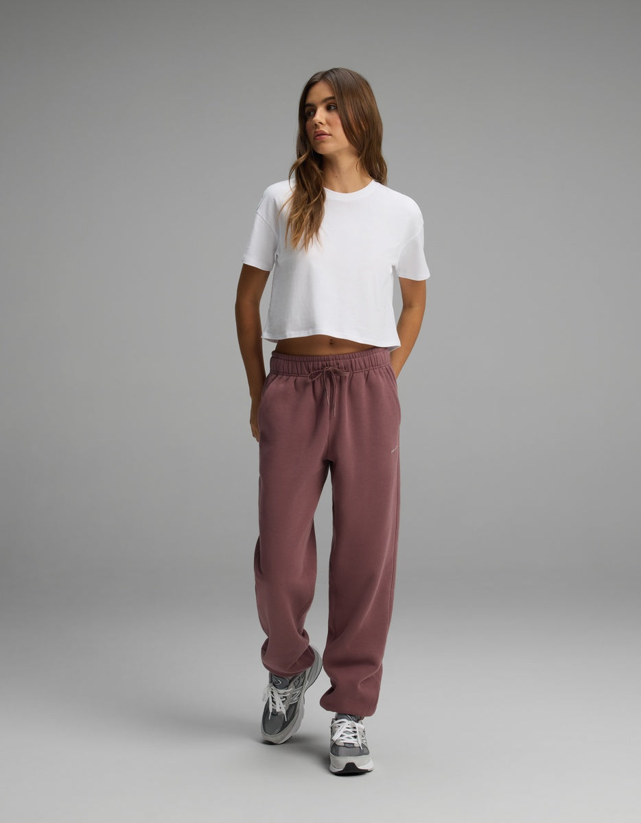A woman wears a white cropped t-shirt and loose-fitting mauve Women’s CityScape Sweatpant with a drawstring waist.