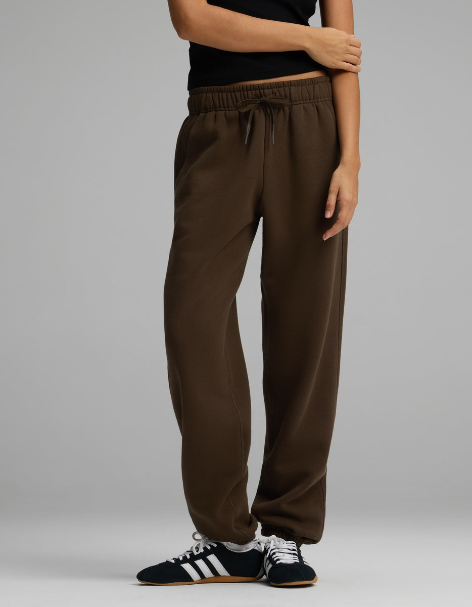 Cozy Earth Women’s CityScape Sweatpant in dark brown with an elastic drawstring waist and cuffed hems, worn with black and white sneakers.