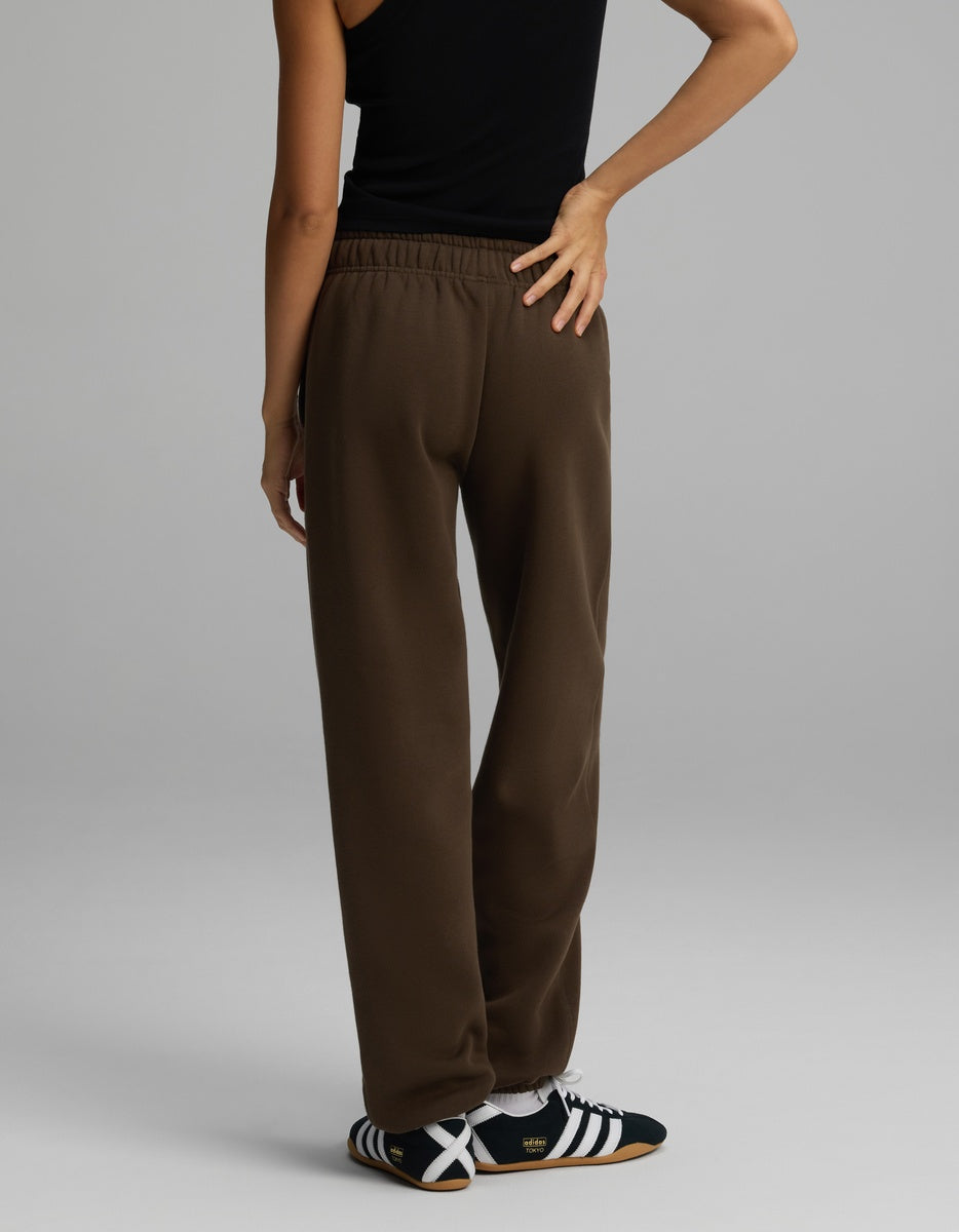 A person wearing brown Women’s CityScape Sweatpant and dark sneakers, viewed from behind.