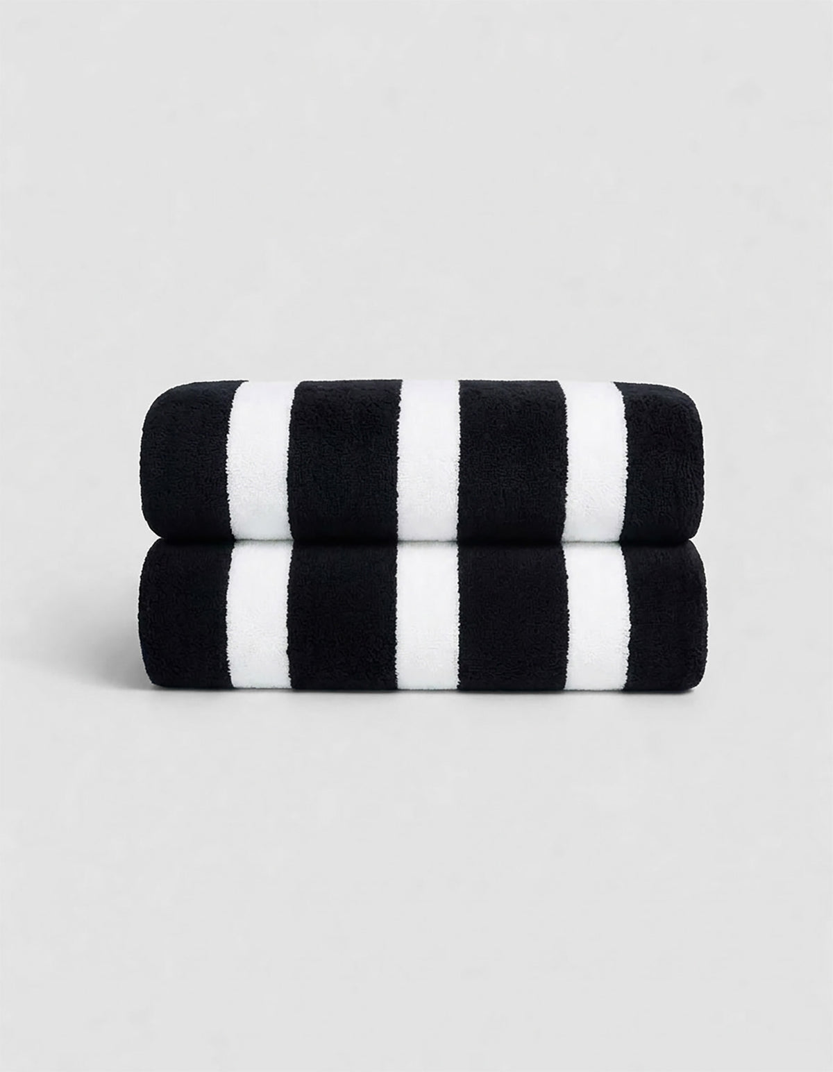 The Cozy Earth Classic Stripe Resort Towel Bundle features two neatly stacked towels with thick black and white stripes, set against a plain light gray background.|Color:Jet Black