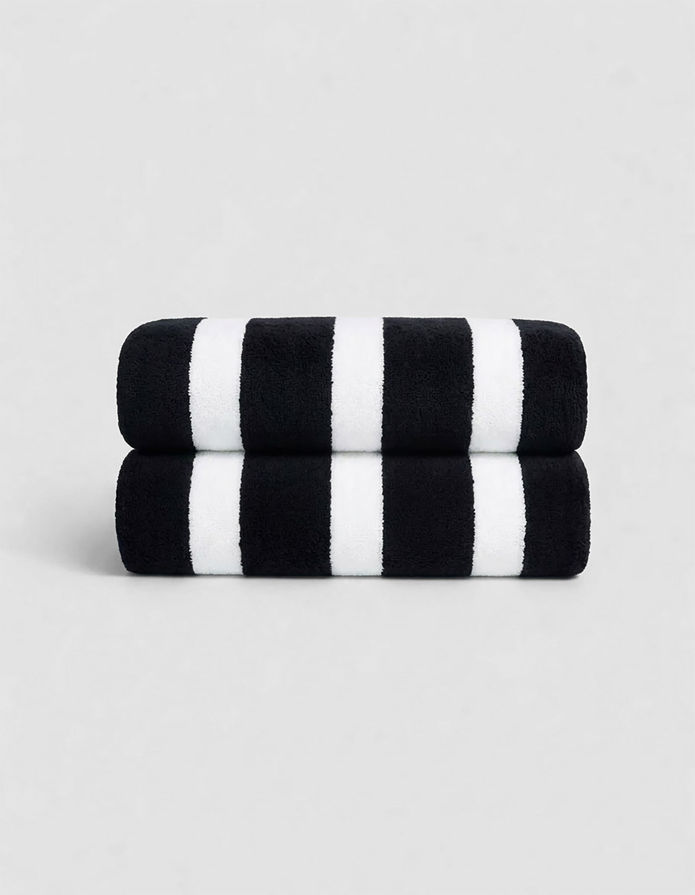 The Cozy Earth Classic Stripe Resort Towel Bundle features two neatly stacked towels with thick black and white stripes, set against a plain light gray background.
