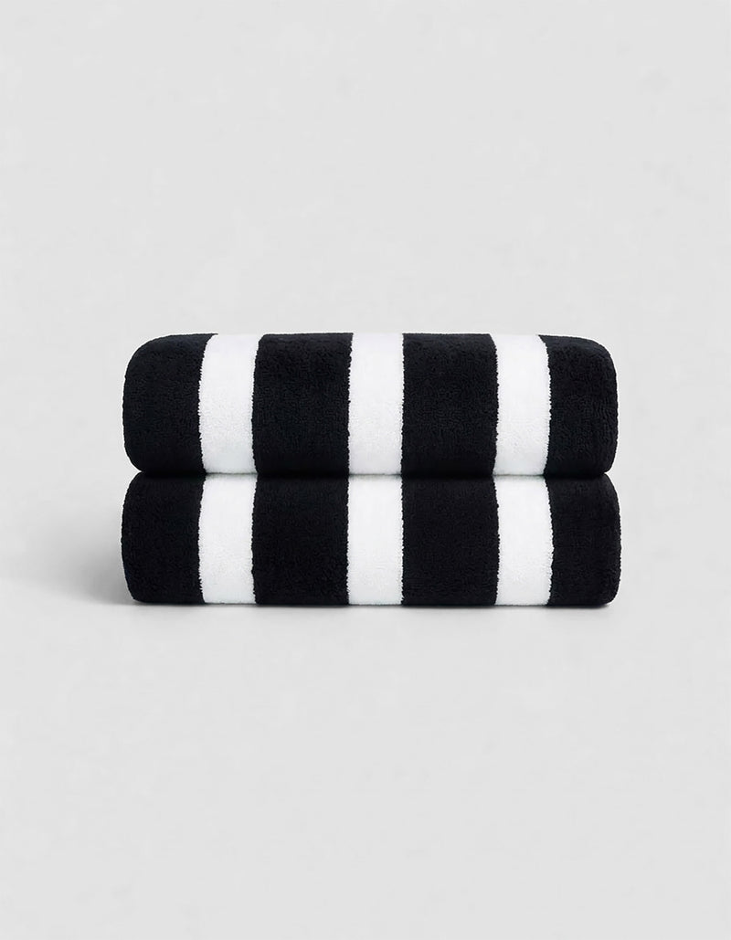 The Cozy Earth Classic Stripe Resort Towel Bundle features two neatly stacked towels with thick black and white stripes, set against a plain light gray background.