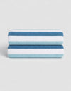The Classic Stripe Resort Towel Bundle by Cozy Earth features two neatly folded towels with dark blue, light blue, and white stripes, stacked together against a plain light background.|Color:Lake Stripe