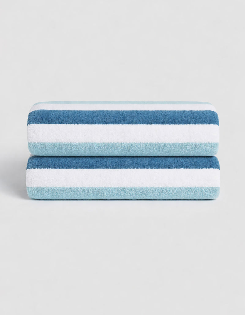 The Classic Stripe Resort Towel Bundle by Cozy Earth features two neatly folded towels with dark blue, light blue, and white stripes, stacked together against a plain light background.