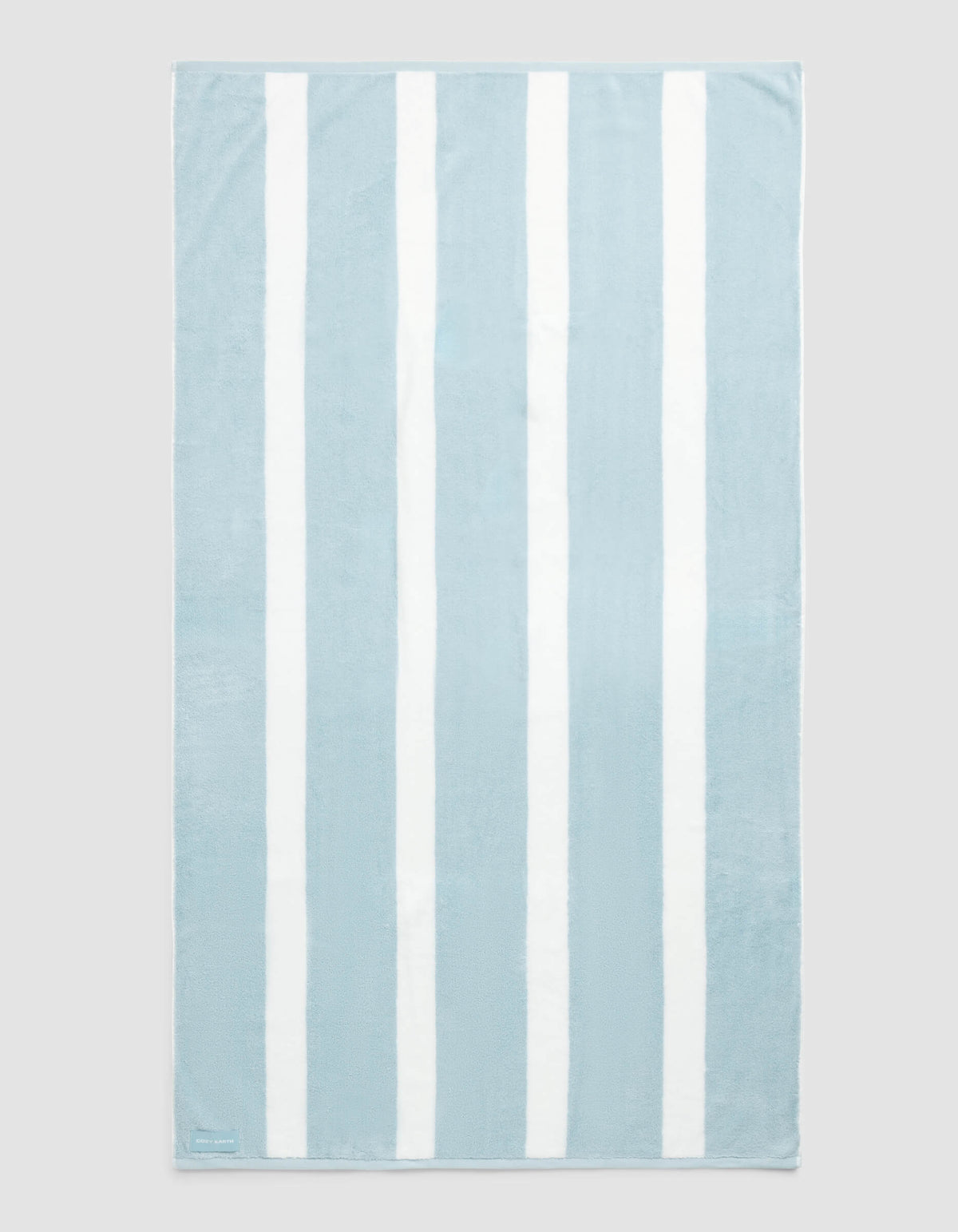 The Cozy Earth Classic Stripe Resort Towel, featuring alternating vertical light blue and white stripes, is laid flat against a plain background.