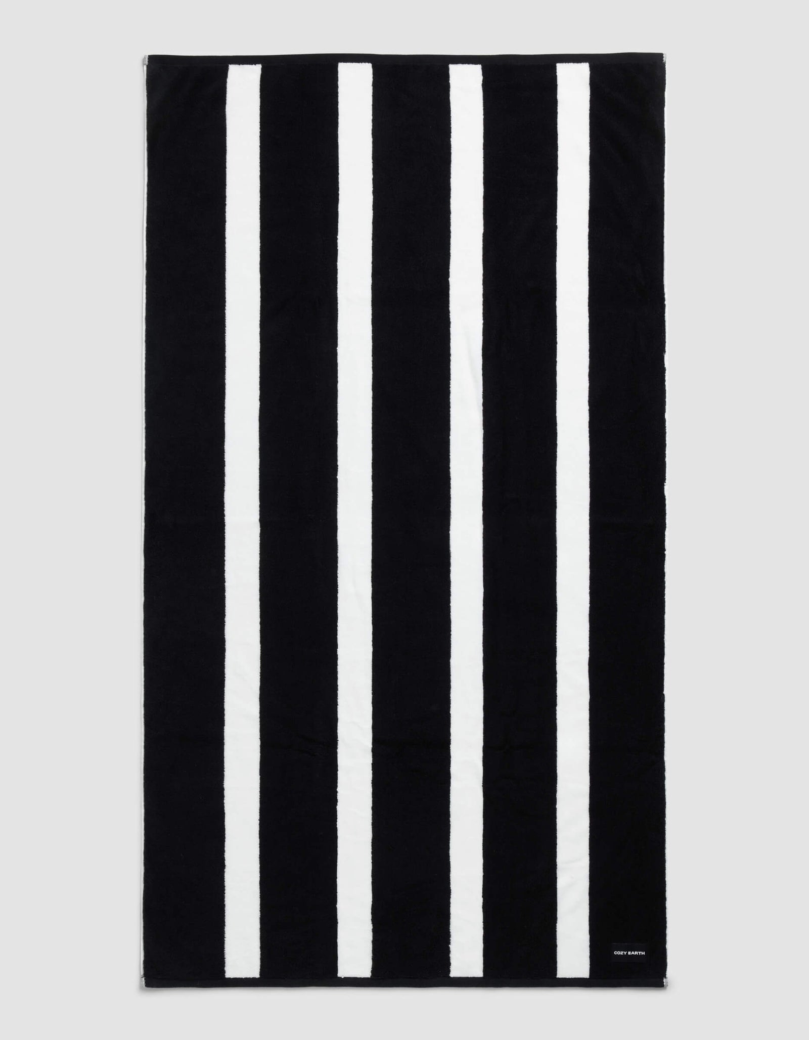 The Cozy Earth Classic Stripe Resort Towel in Jet Black is rectangular with five evenly spaced white stripes and a small white tag with text in the bottom right corner.