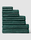 Six towels from the Complete Luxe Bath Bundle by Cozy Earth, featuring a uniform color with seashell stripe, stacked in descending size order on a light gray background.