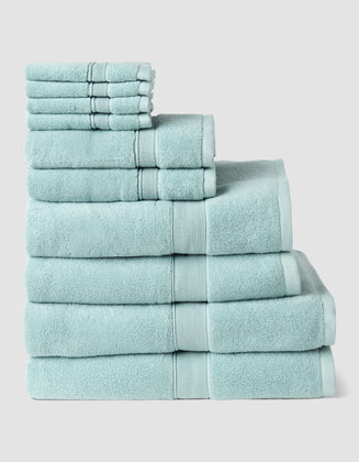 The Complete Luxe Bath Bundle by Cozy Earth features neatly stacked light blue towels in various sizes, arranged from largest to smallest against a plain light background.|Color:Tide
