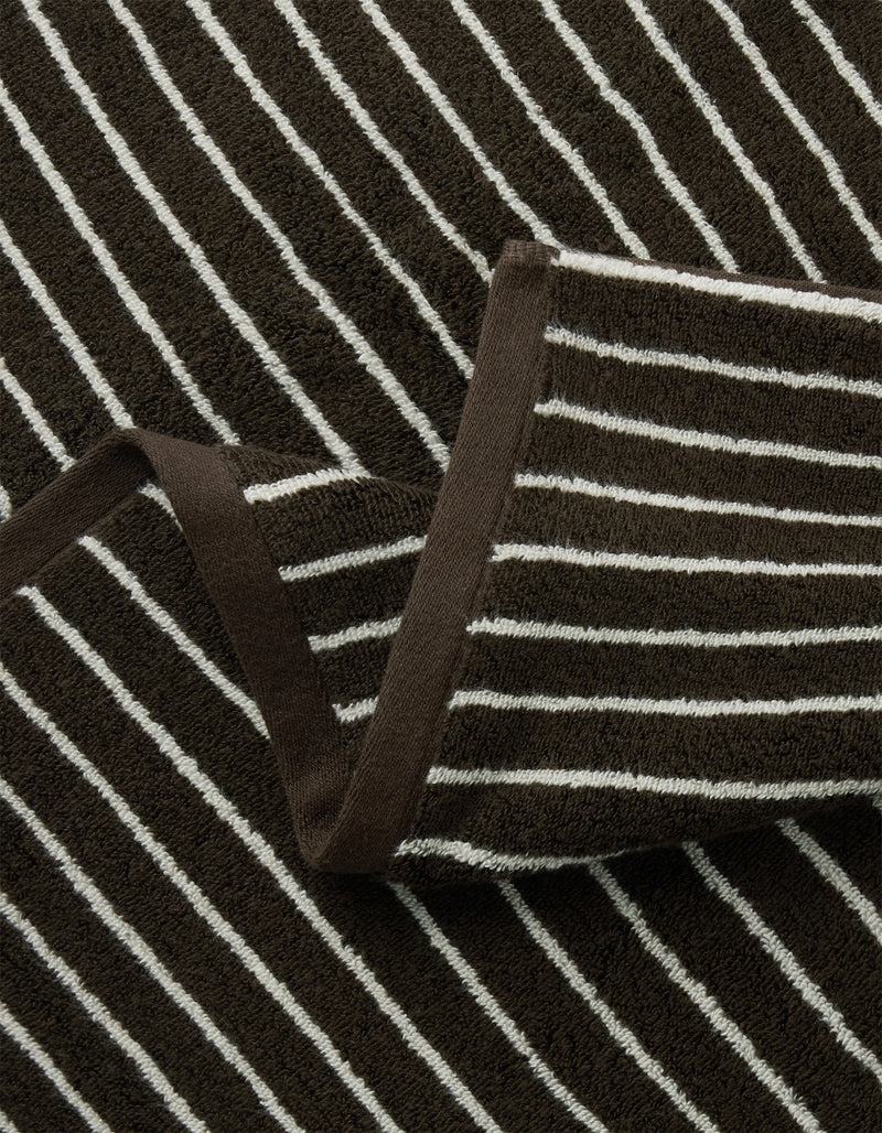 Close-up of the Cozy Earth Complete Striped Luxe Bath Bundle, featuring brown terry cloth with white horizontal stripes, a folded section, and brown trim along the edge.